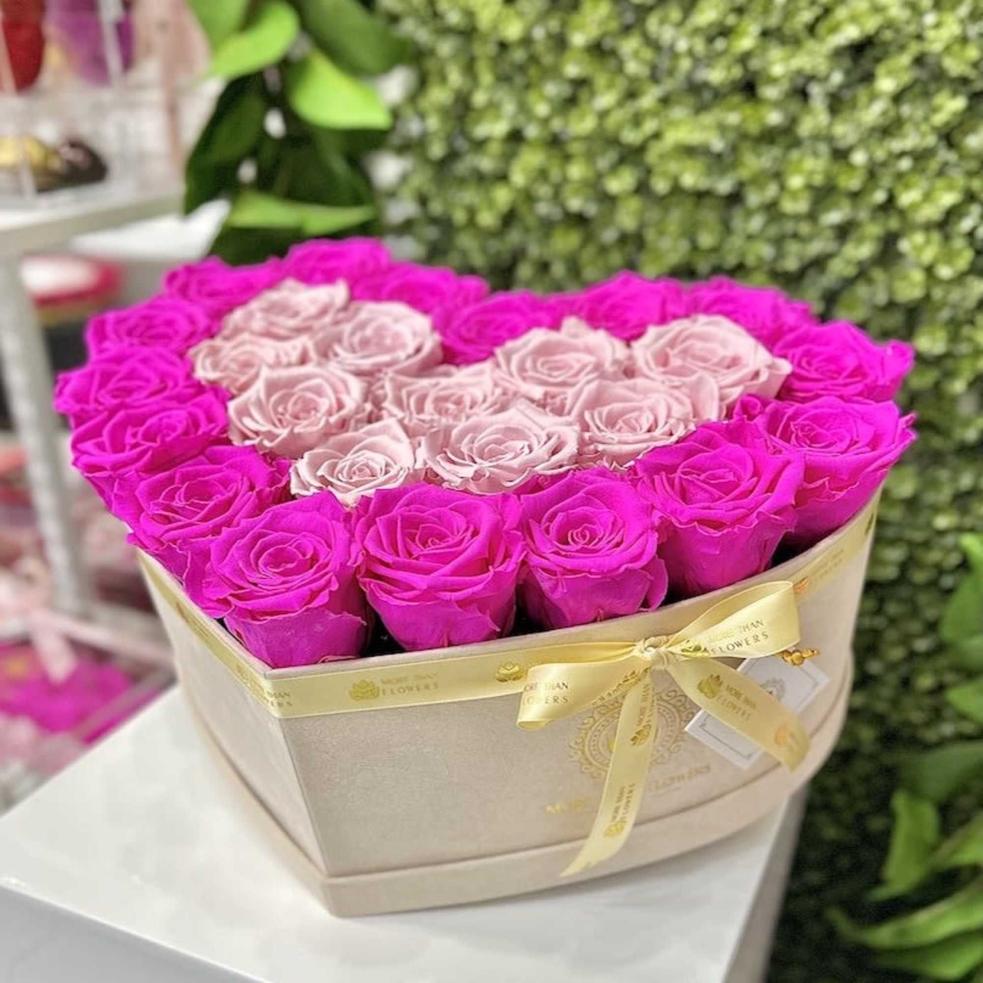 Heart-shaped box of hot pink and pale pink roses tied with a satin ribbon