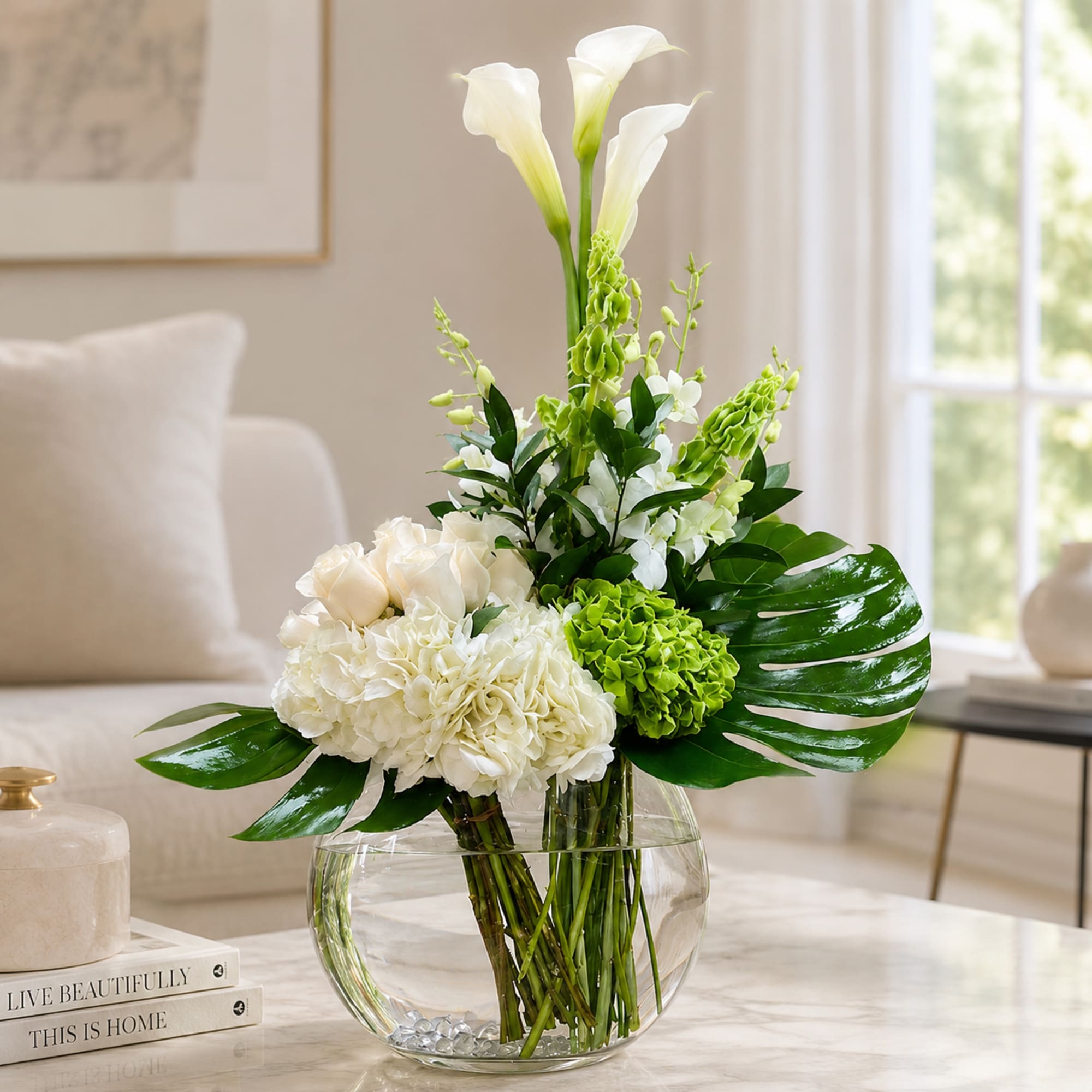 White and green floral arrangement in a round glass vase