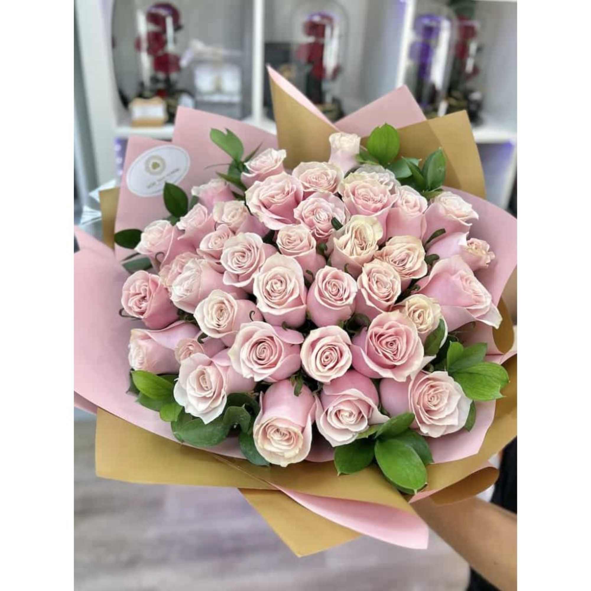 Large bouquet of pale pink roses wrapped in pink and tan paper