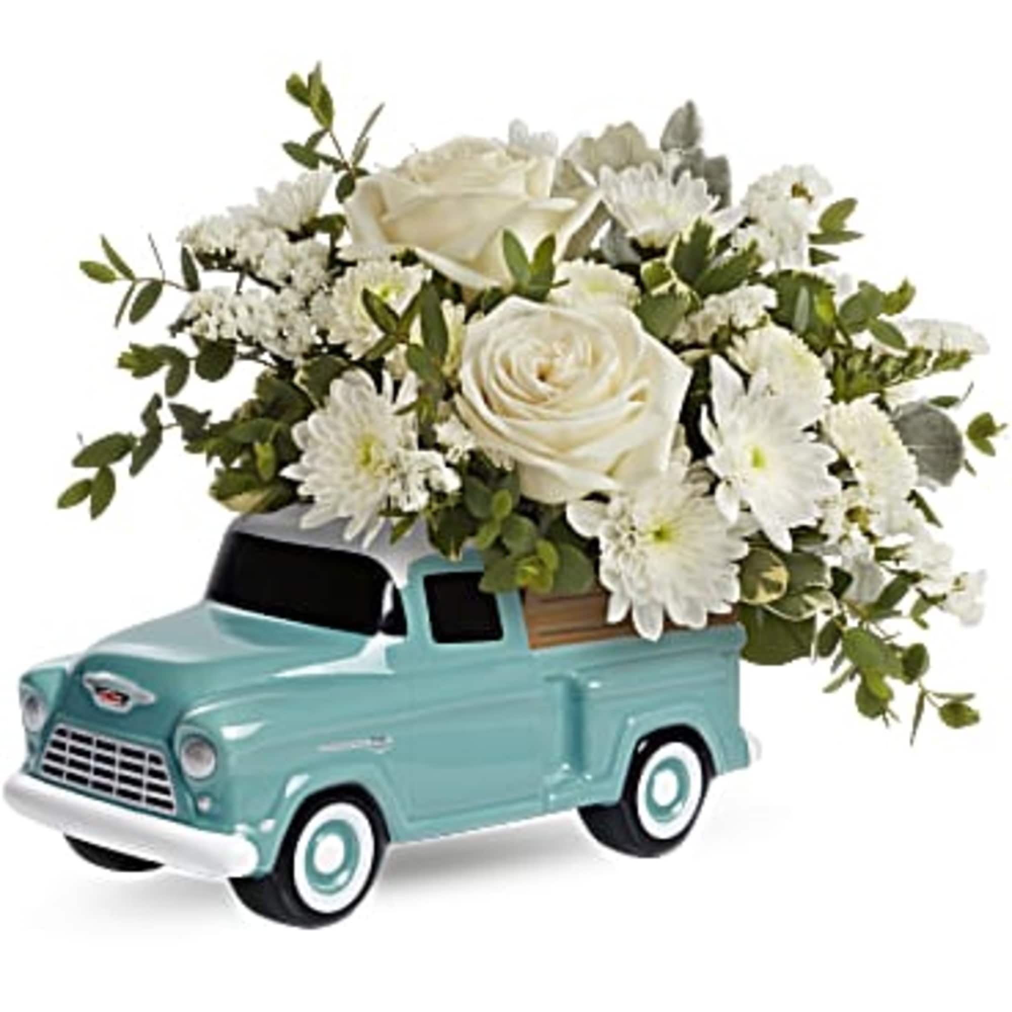 White roses and daisies arranged in a turquoise toy truck