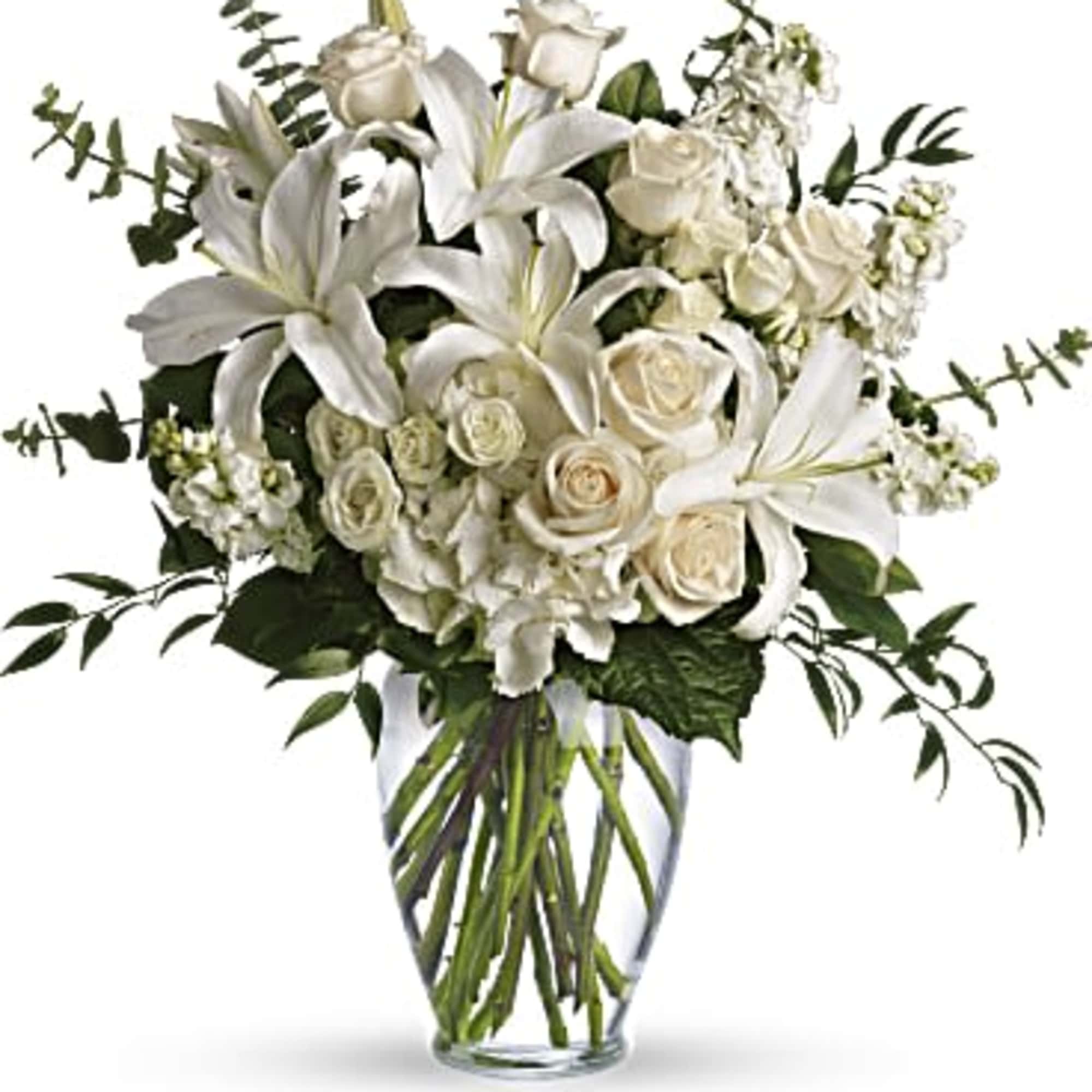 White lilies and roses arranged in a clear glass vase