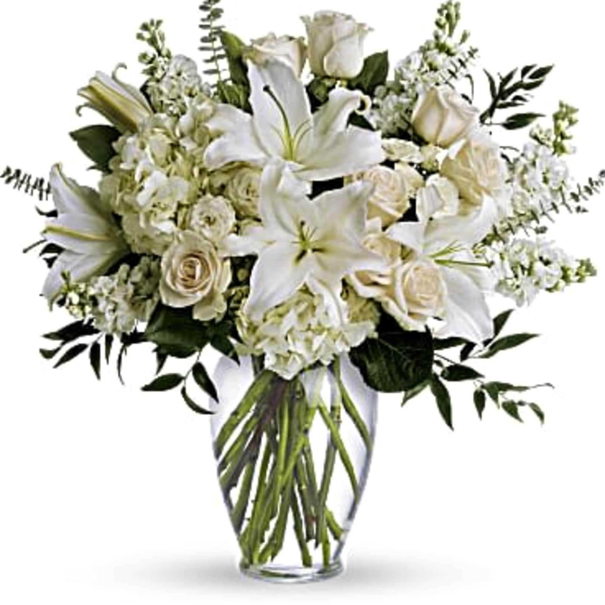 White lilies and roses arranged in a clear glass vase