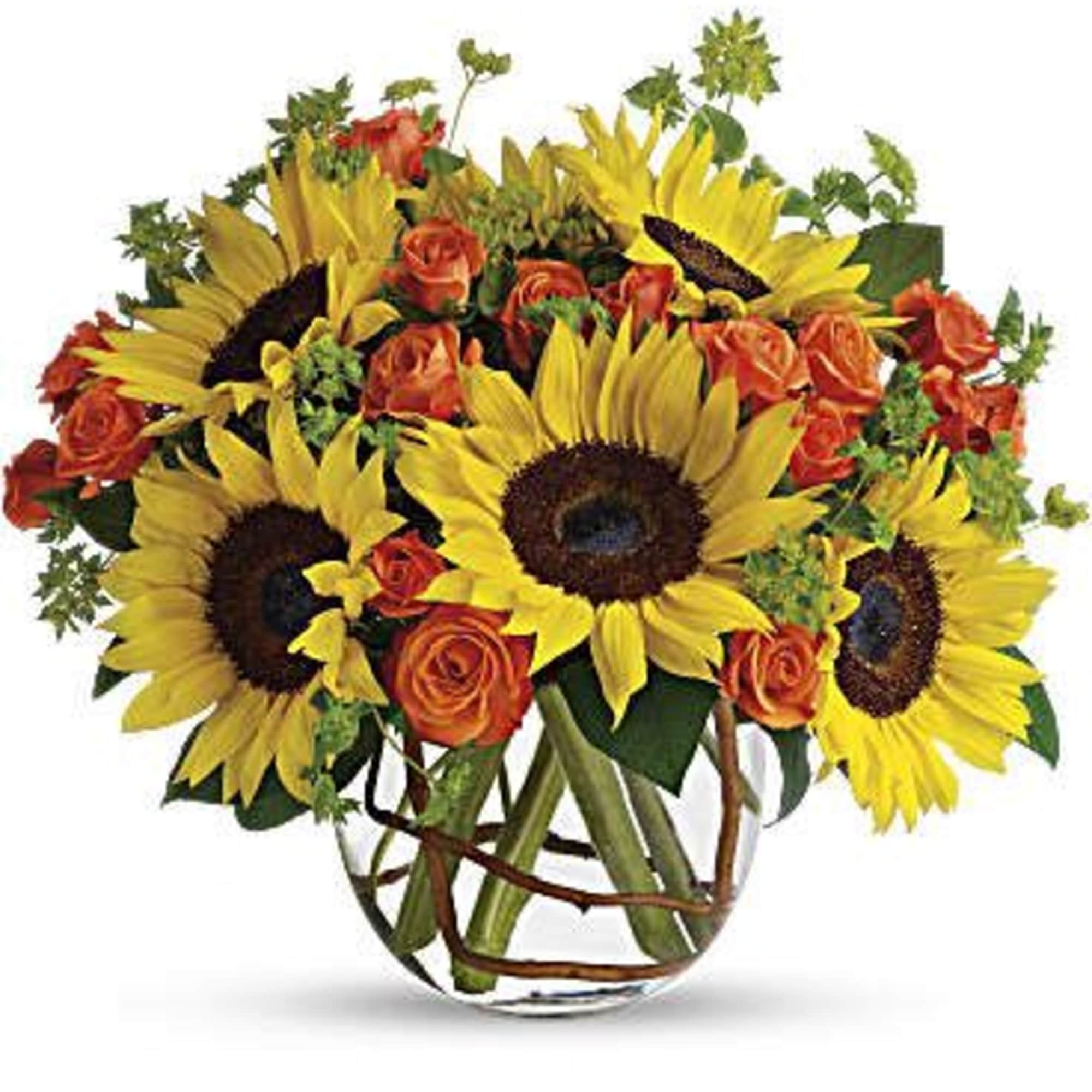 Sunflowers and orange roses arranged in a clear glass vase