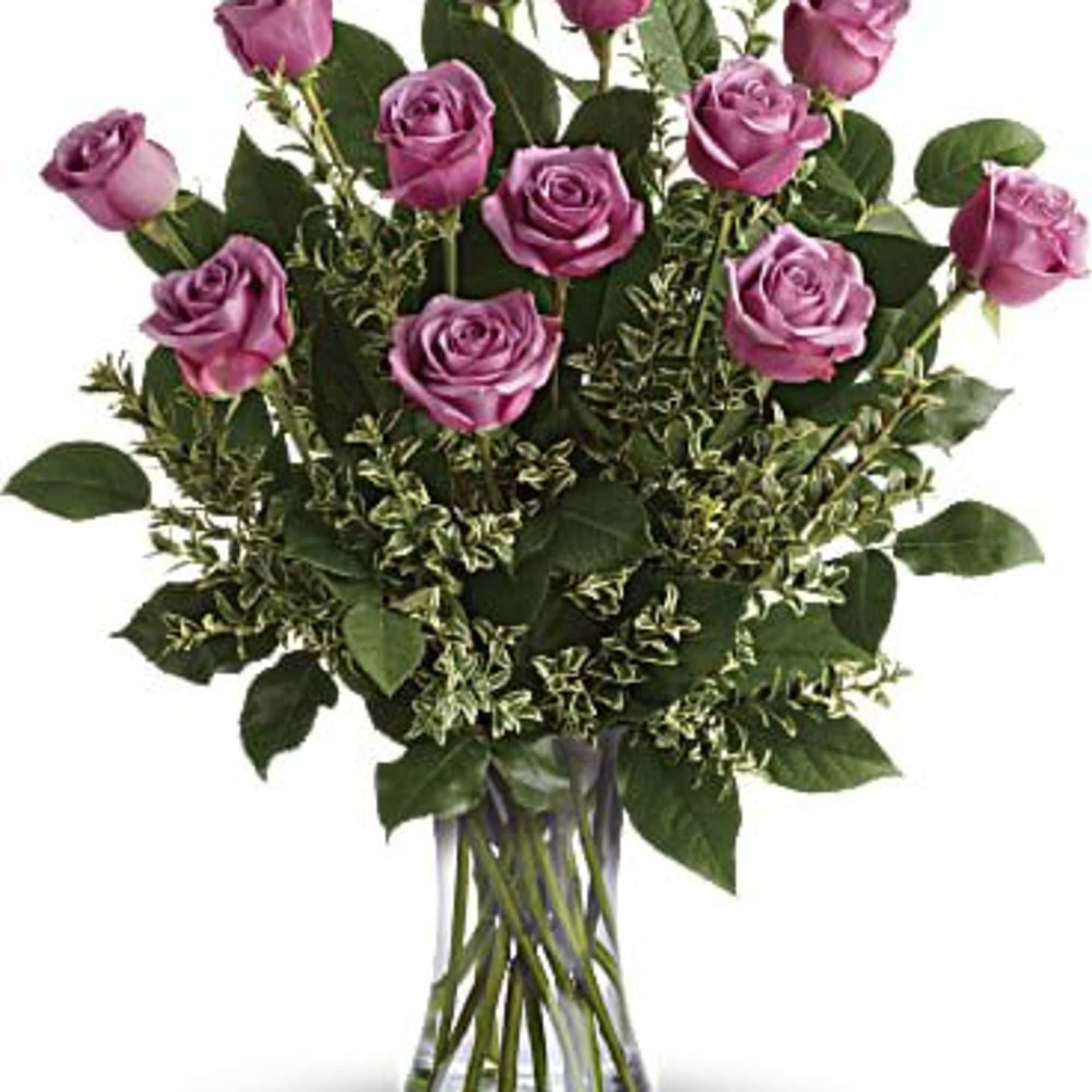 Purple roses in a clear glass vase with greenery