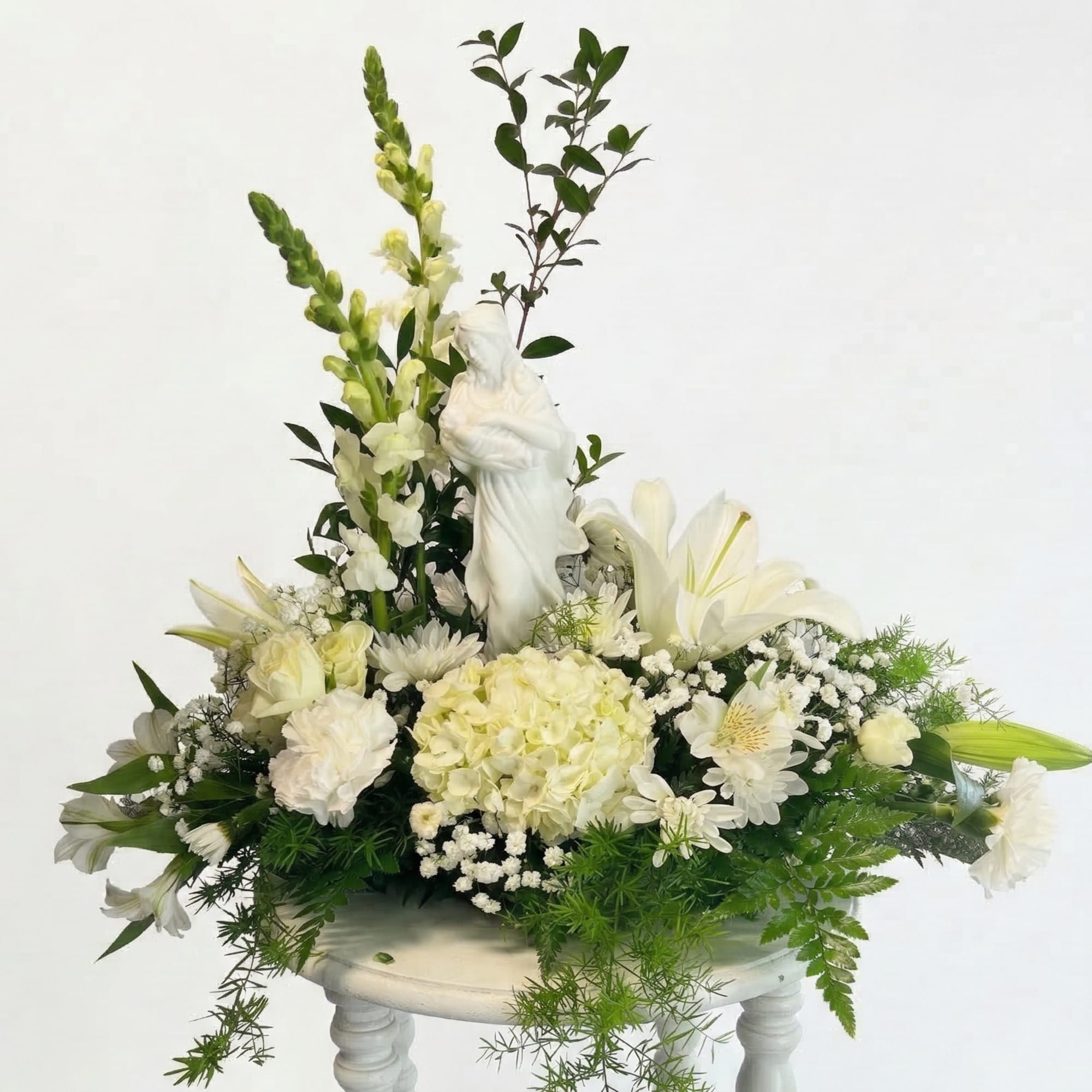 White floral arrangement with a religious statue in the center