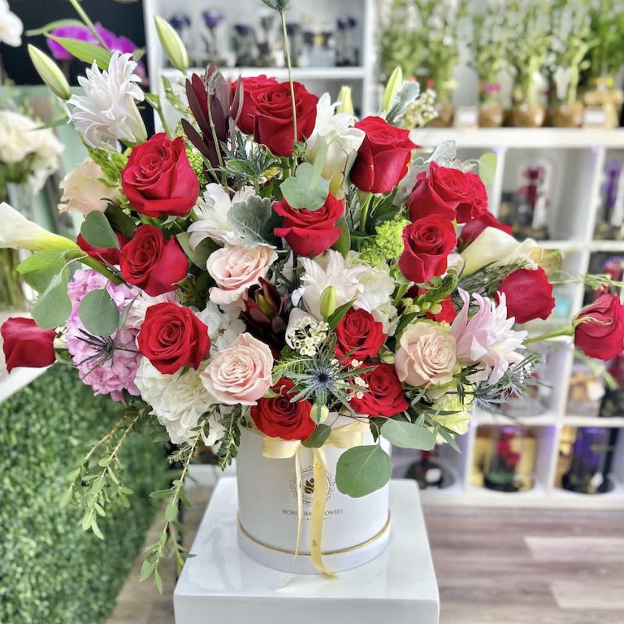 Large mixed bouquet of red and pastel flowers in a white hatbox container