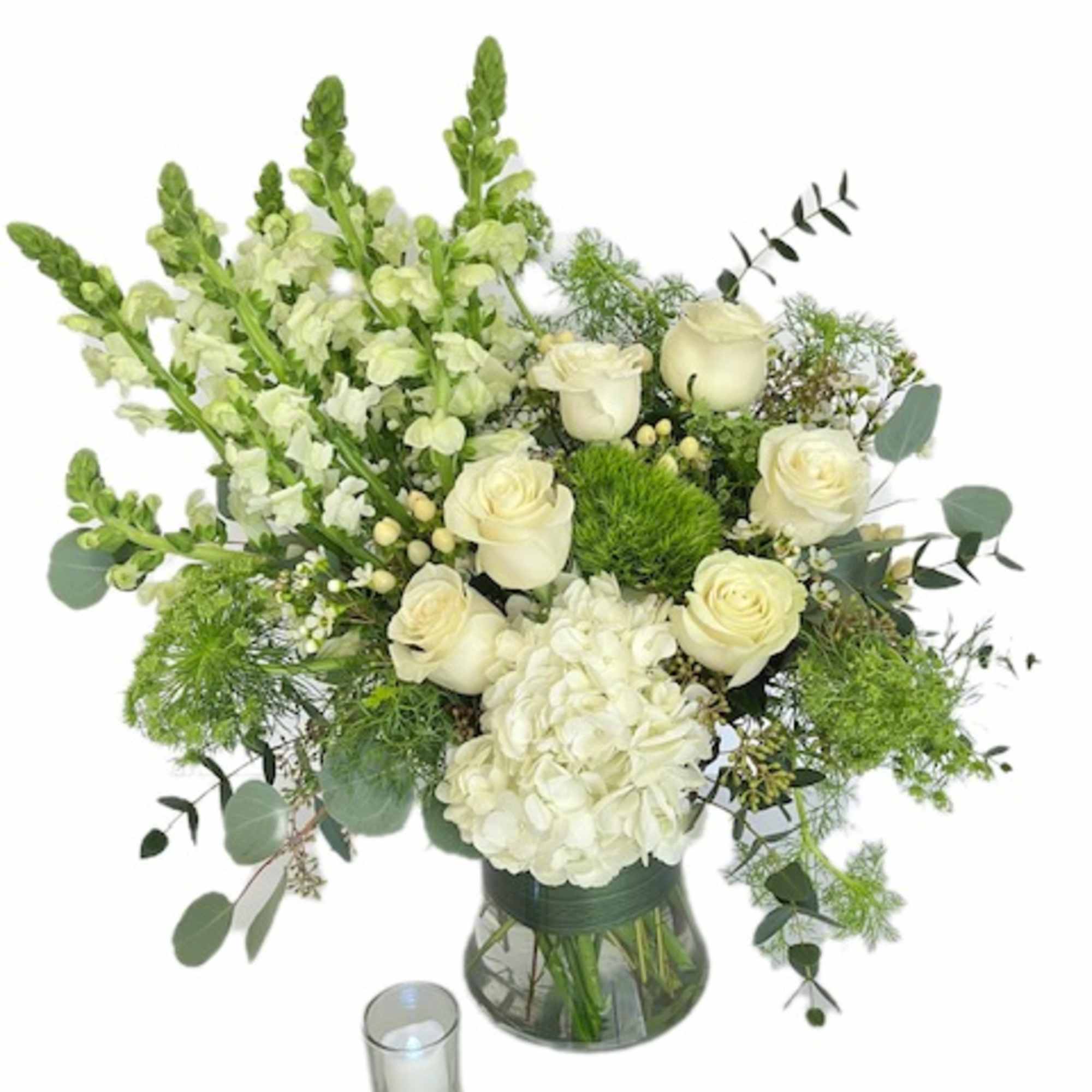 White roses and hydrangea in a glass vase with a small candle