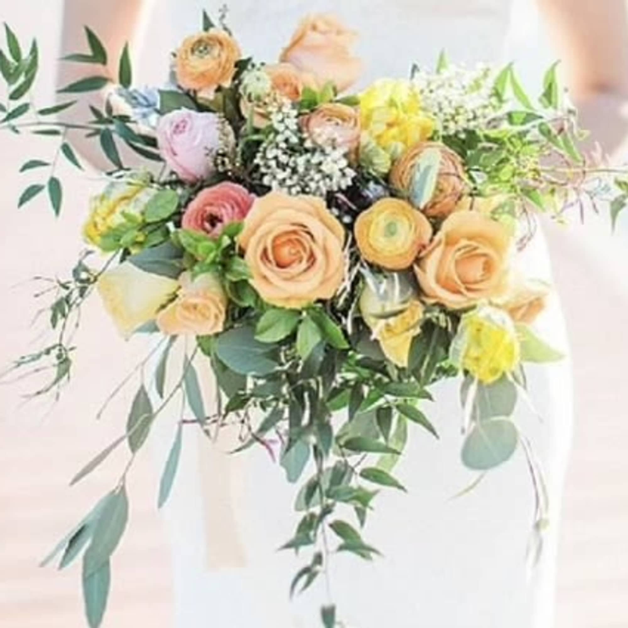 Bouquet of peach, pink, and yellow flowers with trailing greenery