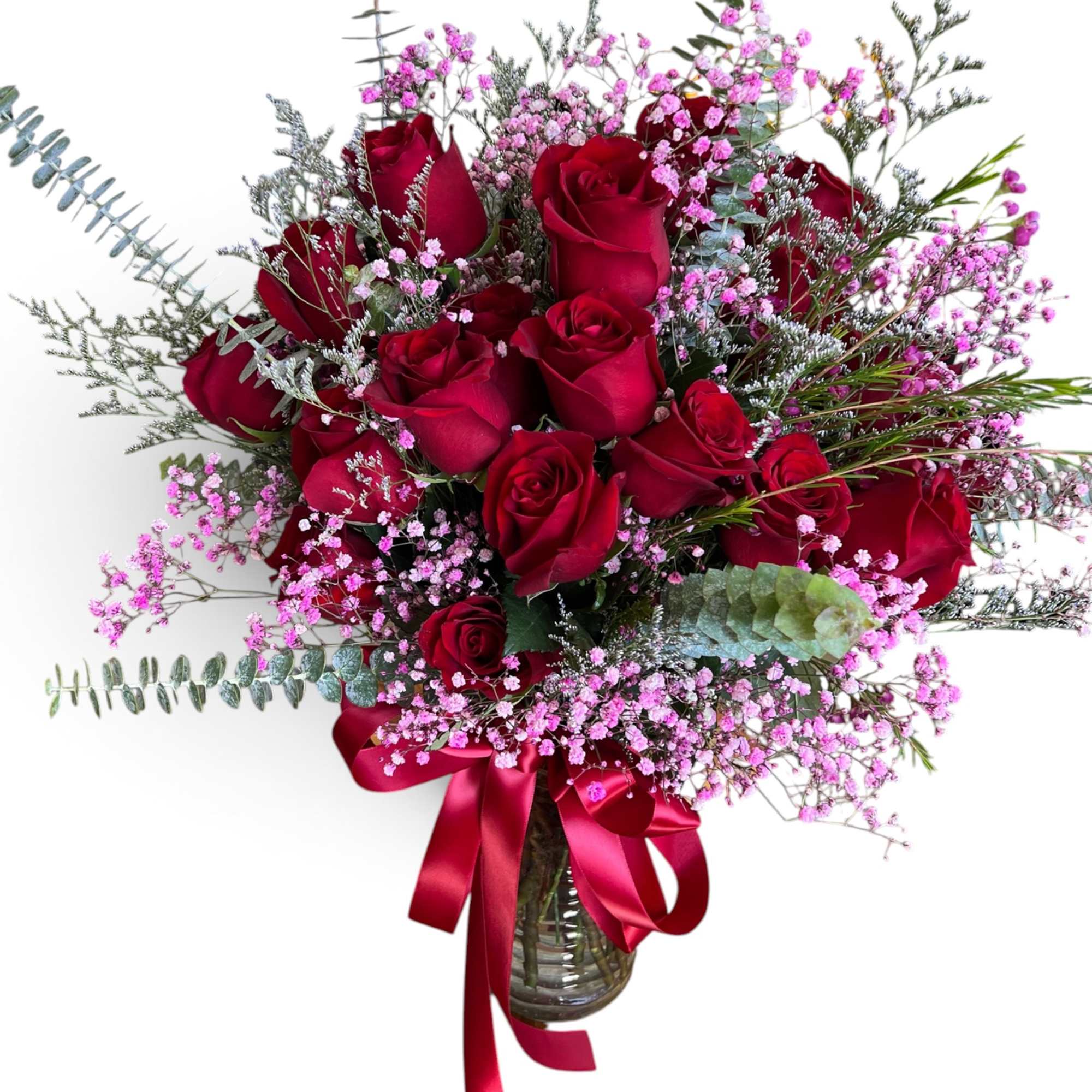 Red roses in a glass vase with pink filler flowers and a red ribbon