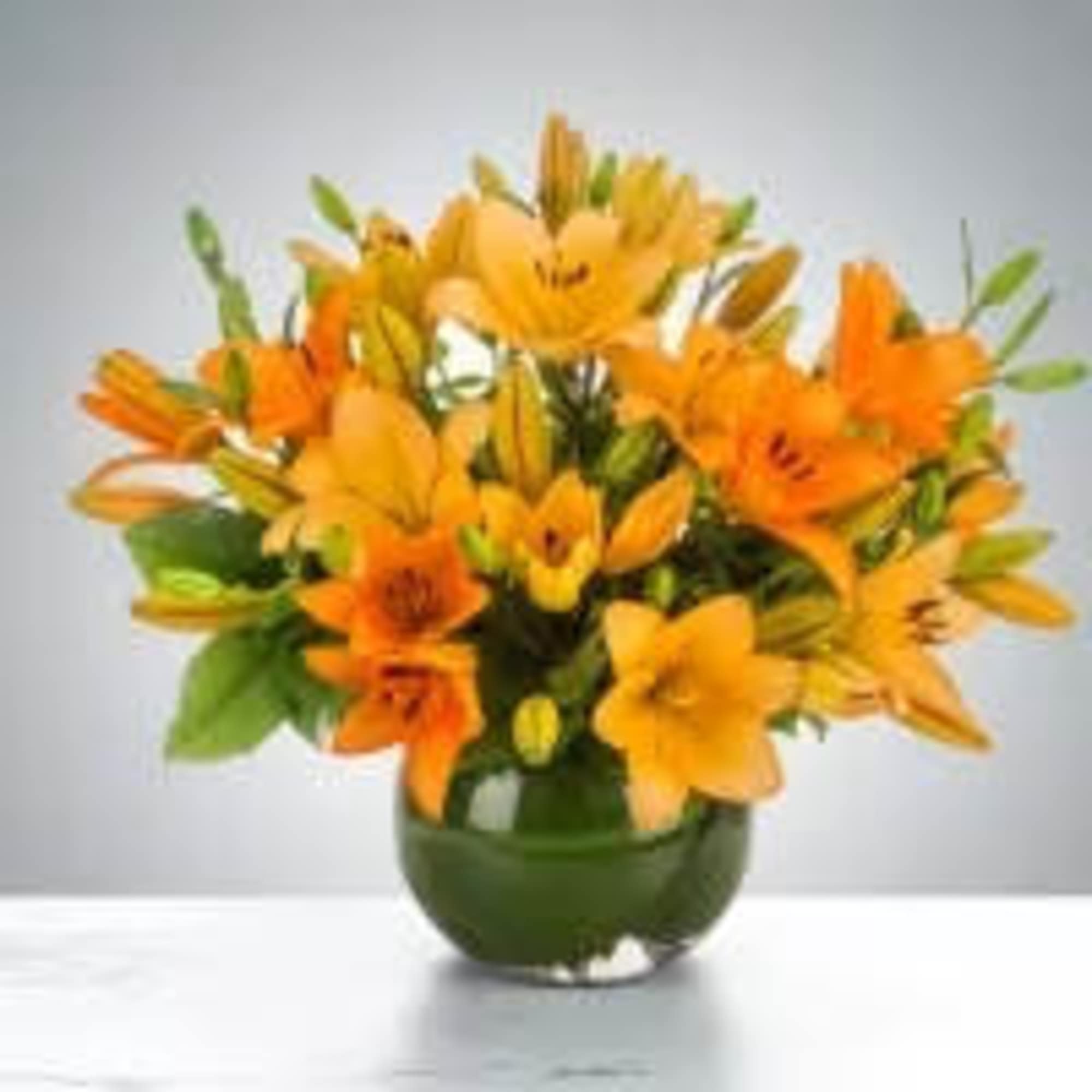 Orange lily bouquet in a green glass vase