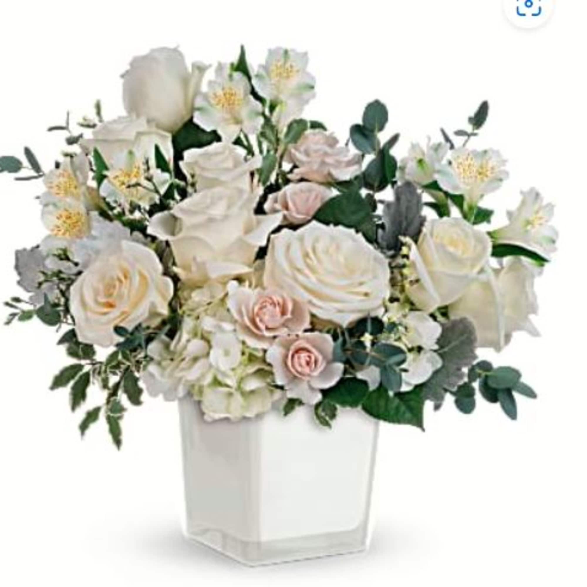 White and blush floral arrangement in a clear square vase