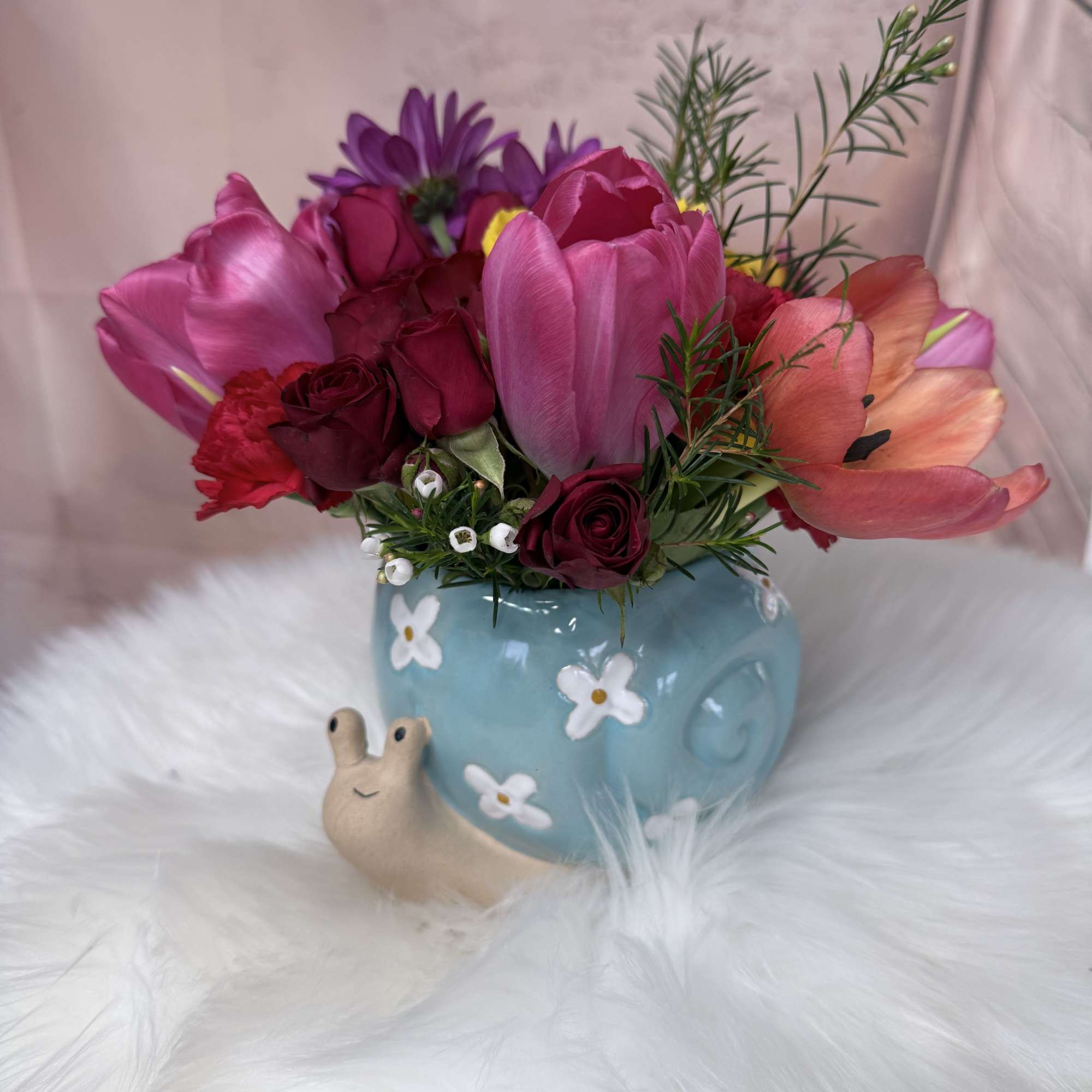 A sweet and charming arrangement featuring delicate flowers and fresh seasonal foliage