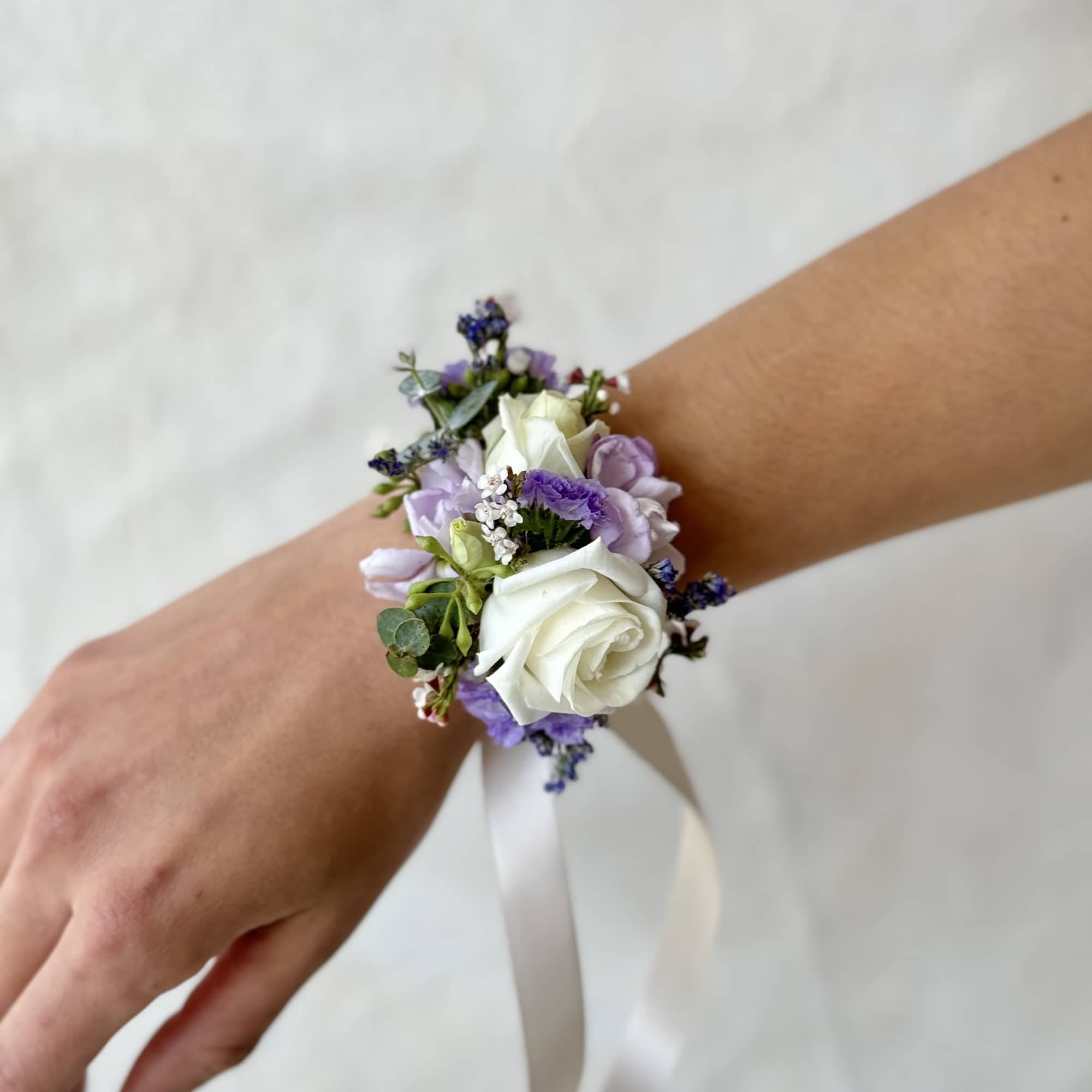 White and lavender wrist corsage with ribbon