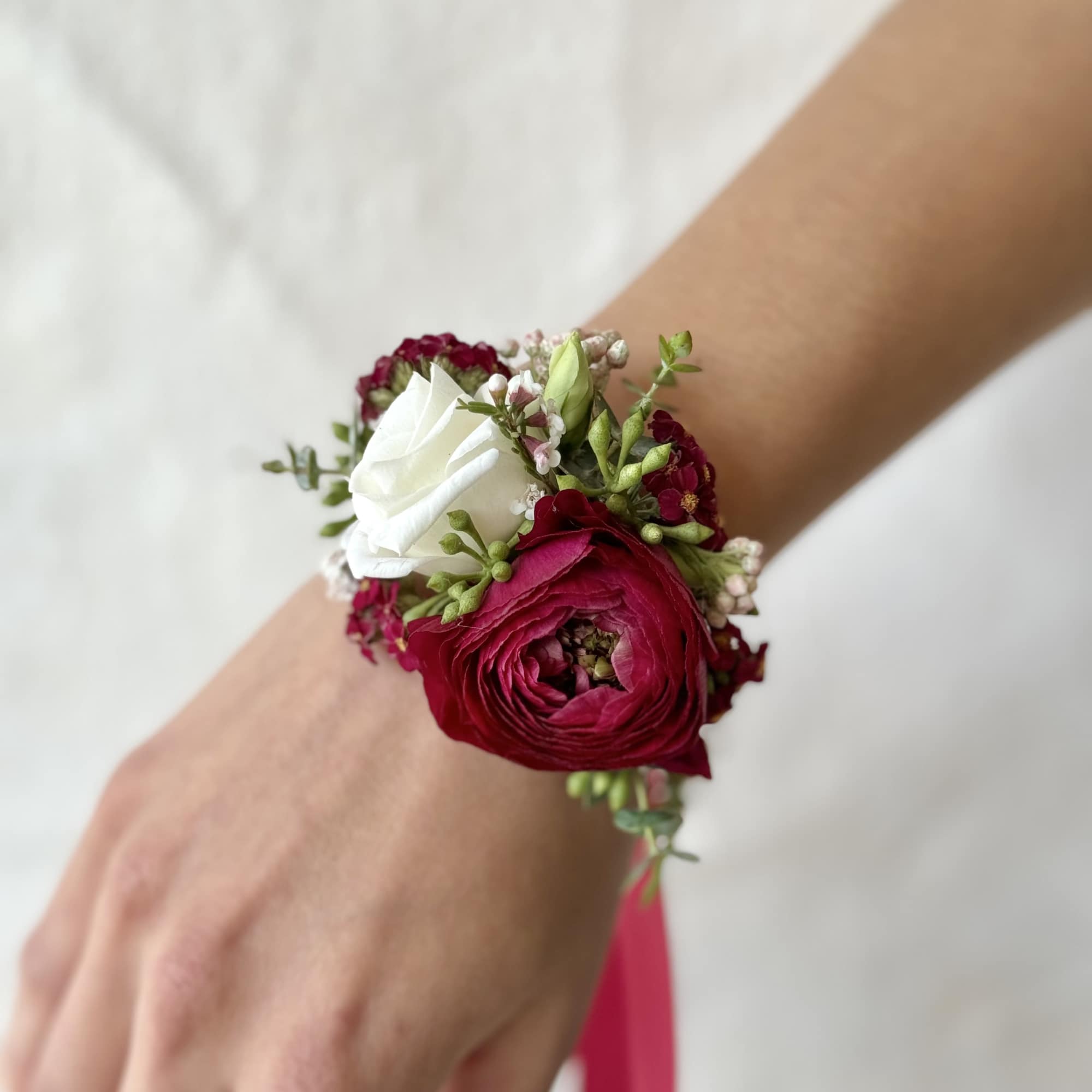 Red and white floral wrist corsage on a person's wrist