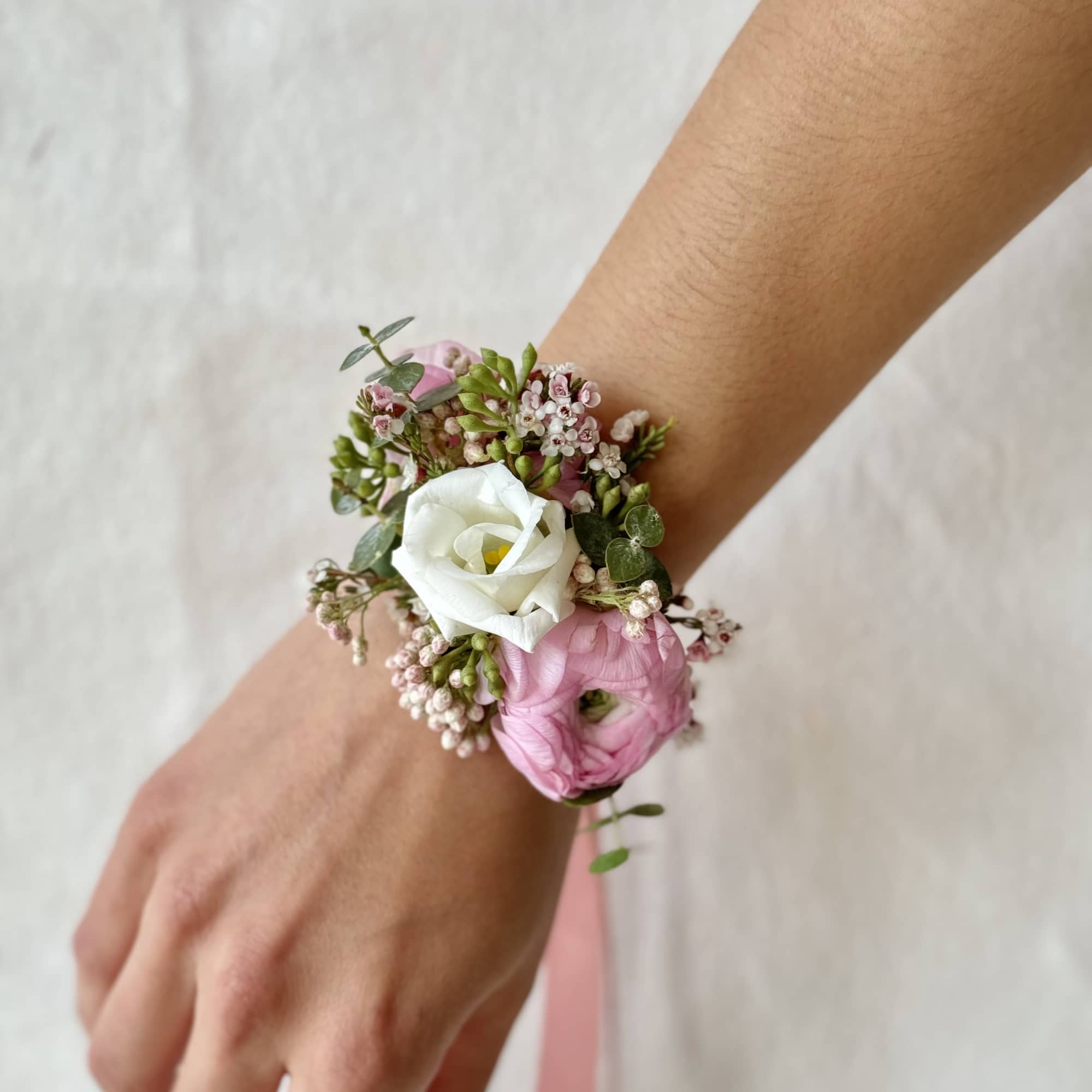 Pink and white floral wrist corsage on a person's wrist