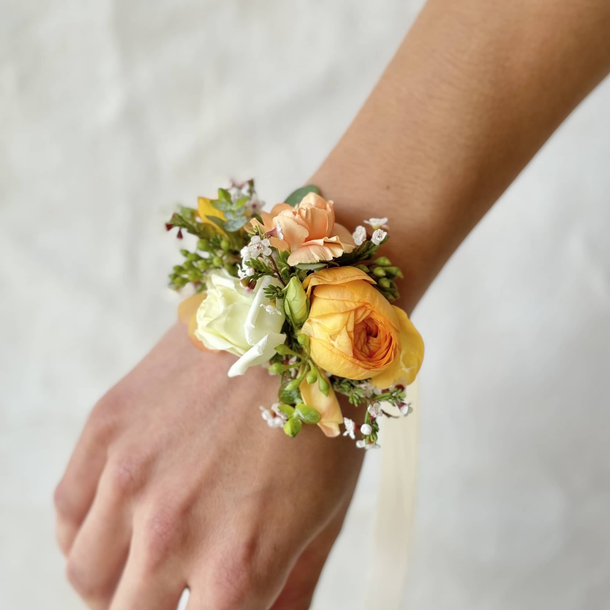 Floral wrist corsage with peach, yellow, and white blooms