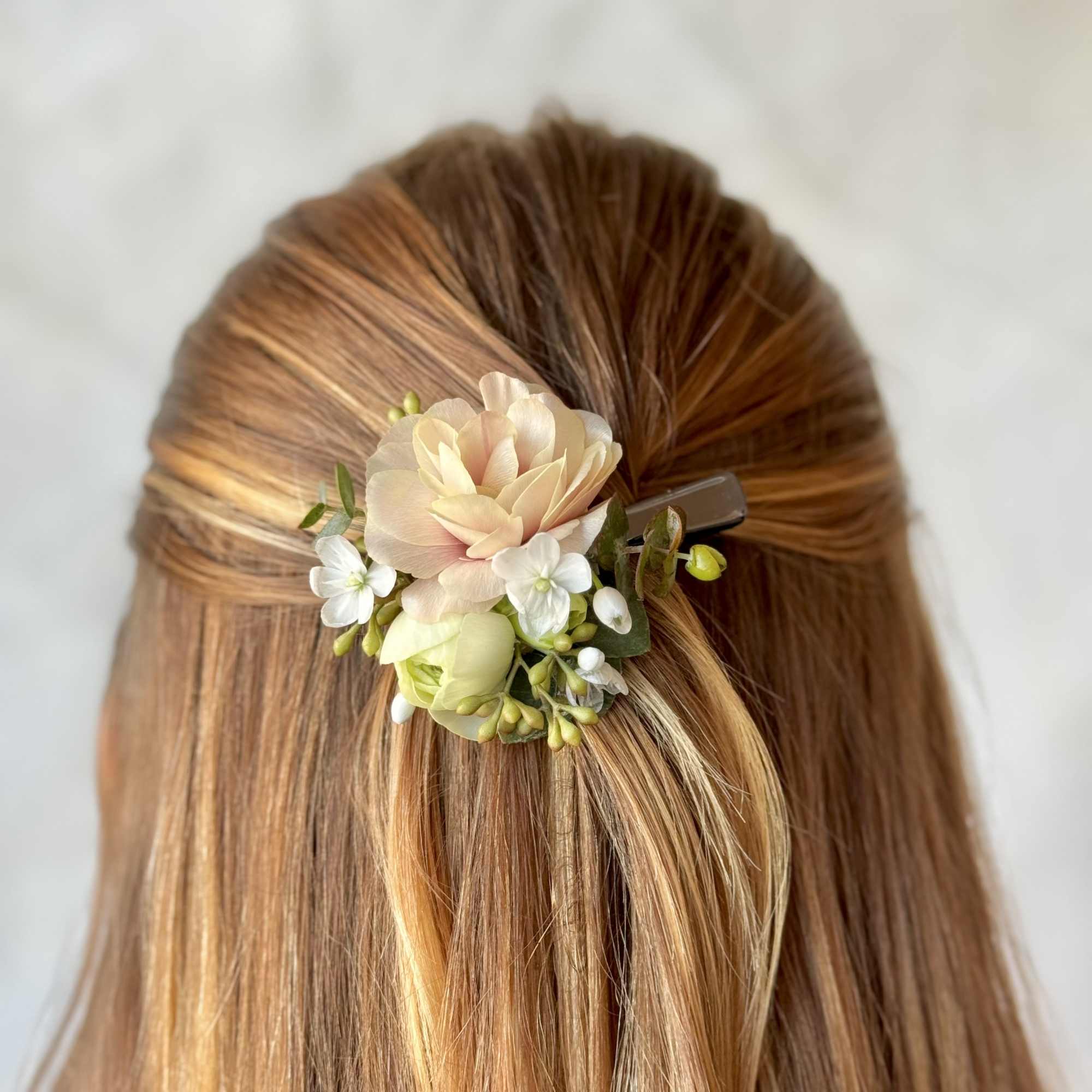 Floral hair clip with pale peach and white blossoms in brown hair