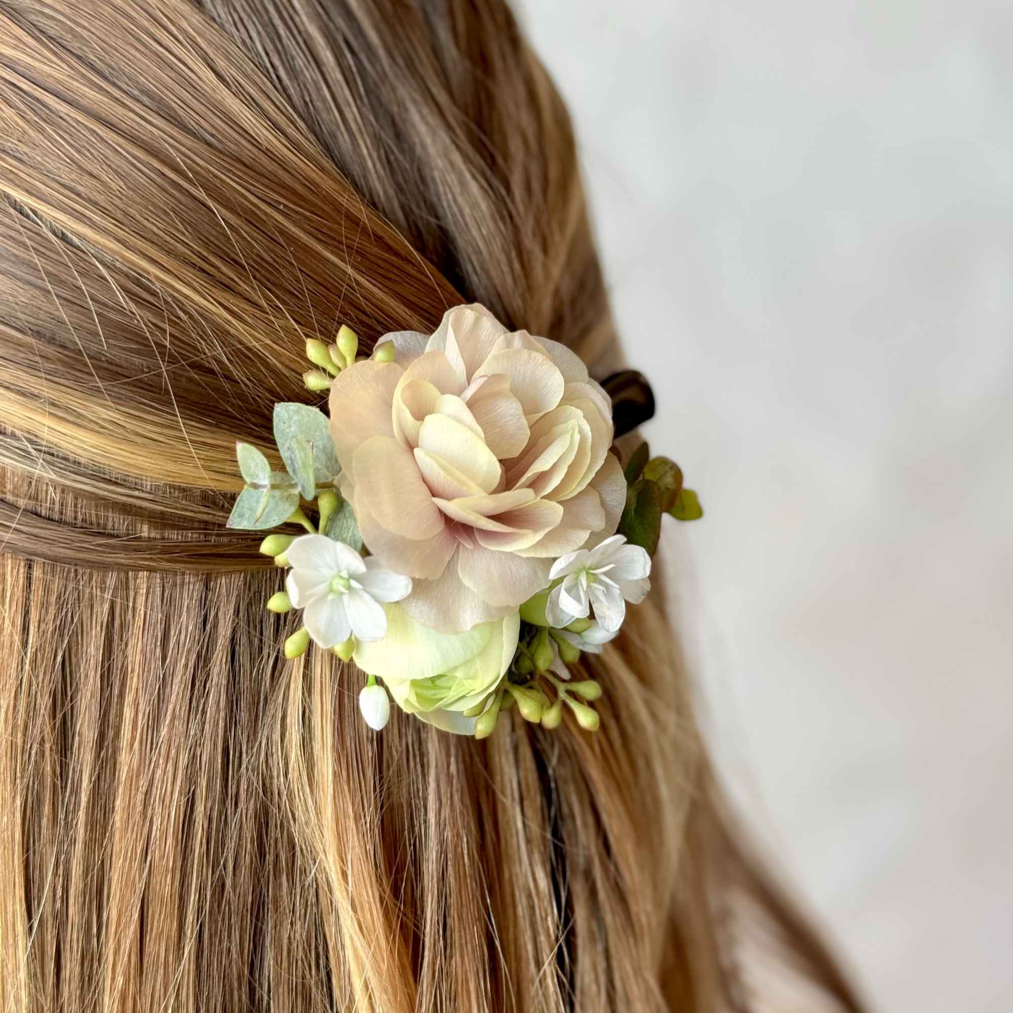 Floral hair accessory with pale peach and white blossoms in blonde hair