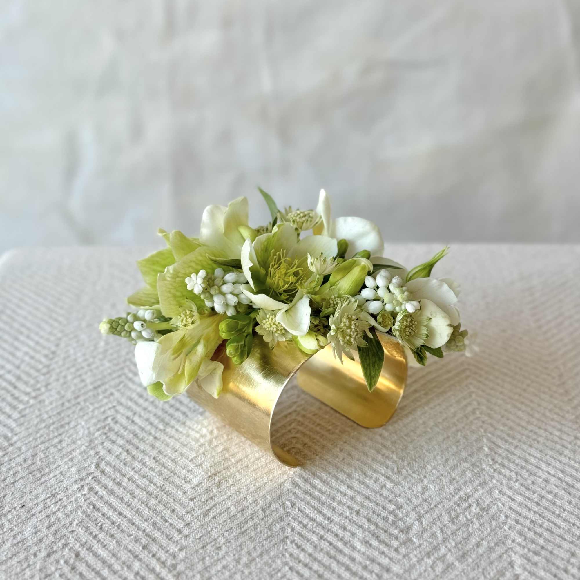 Small white and green floral cuff bracelet on a gold band