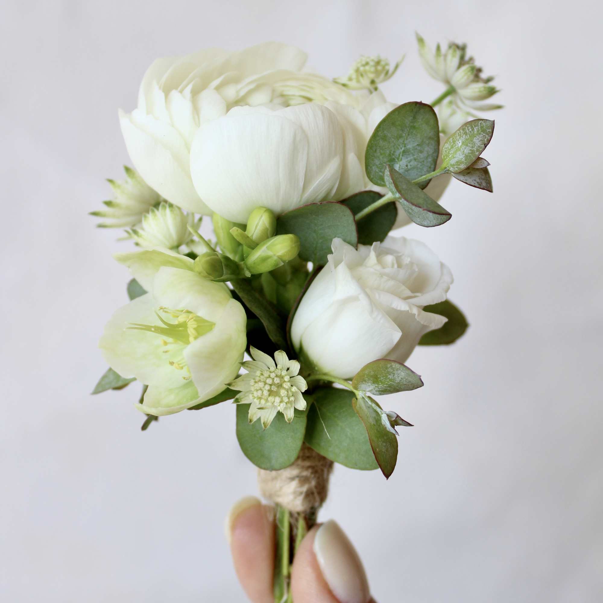 Small white flower boutonniere with green foliage