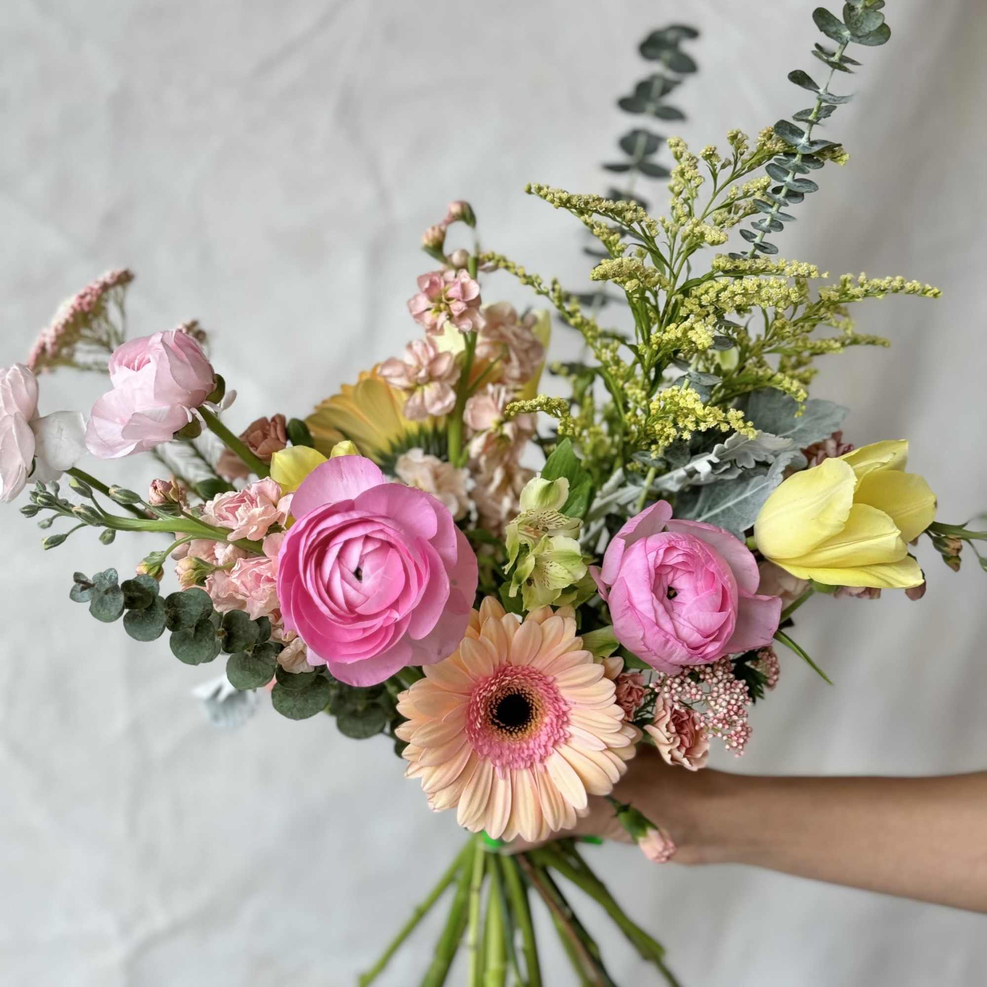 Hand-tied bouquet of pink and peach flowers with eucalyptus
