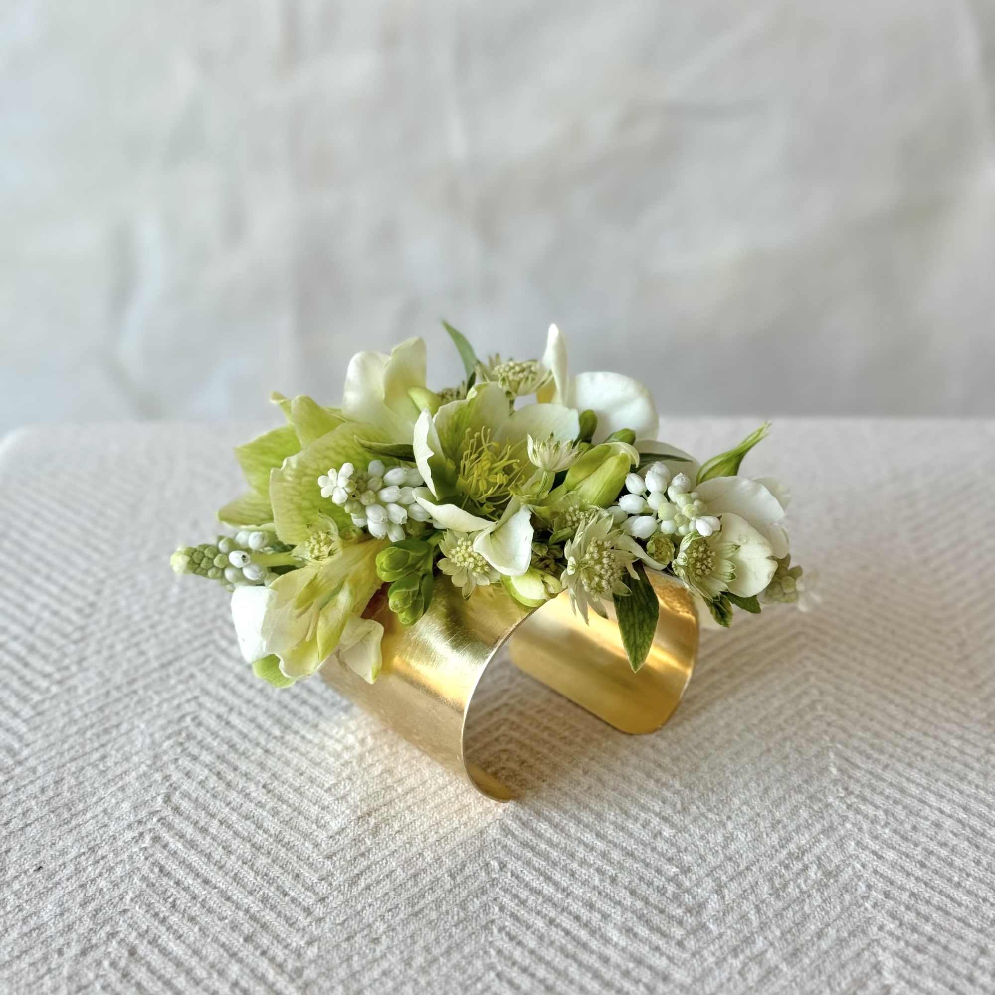 Small white and green floral cuff bracelet on a gold band