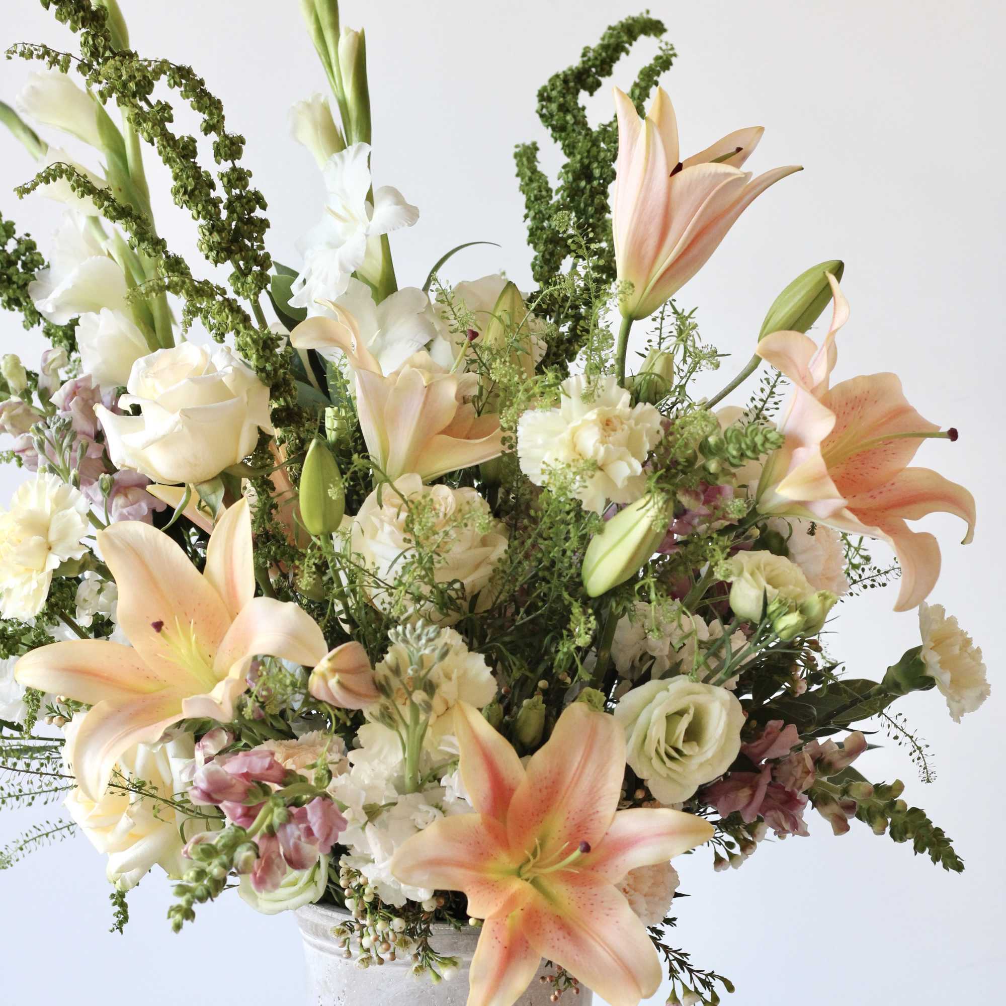 Tall bouquet of peach lilies and white roses in a gray vase