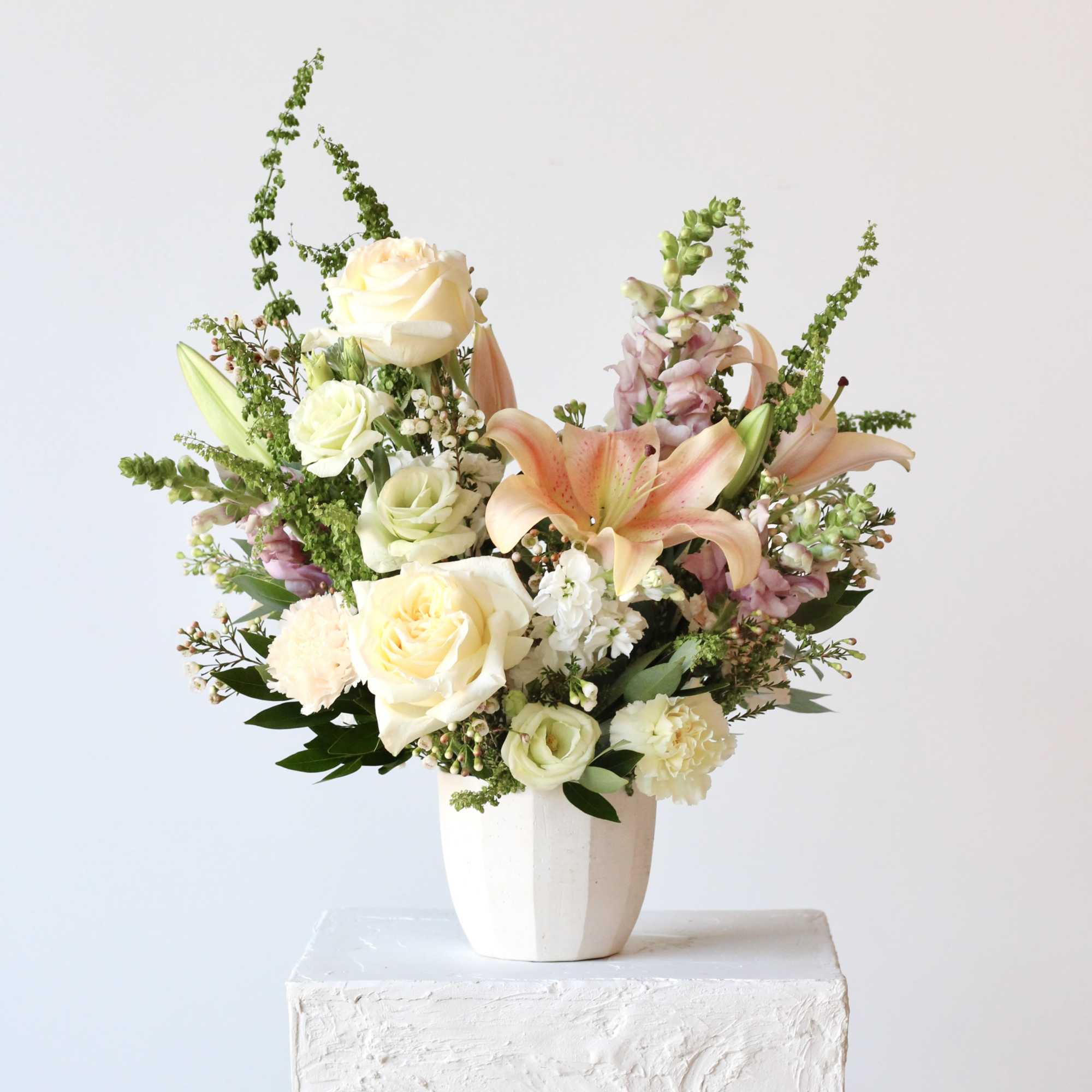 Cream roses and peach lilies in a white vase