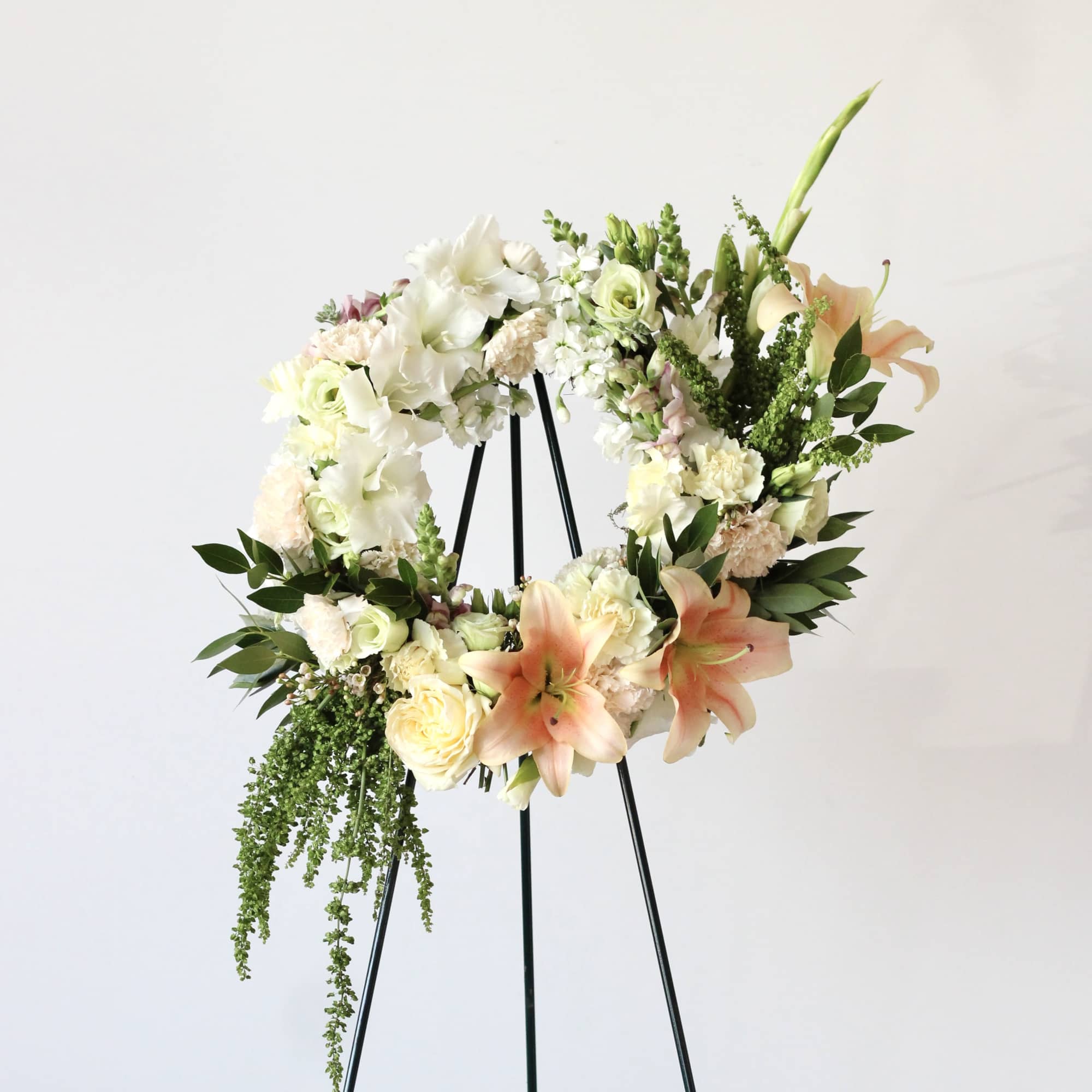 Floral wreath on a black easel with white and peach blooms