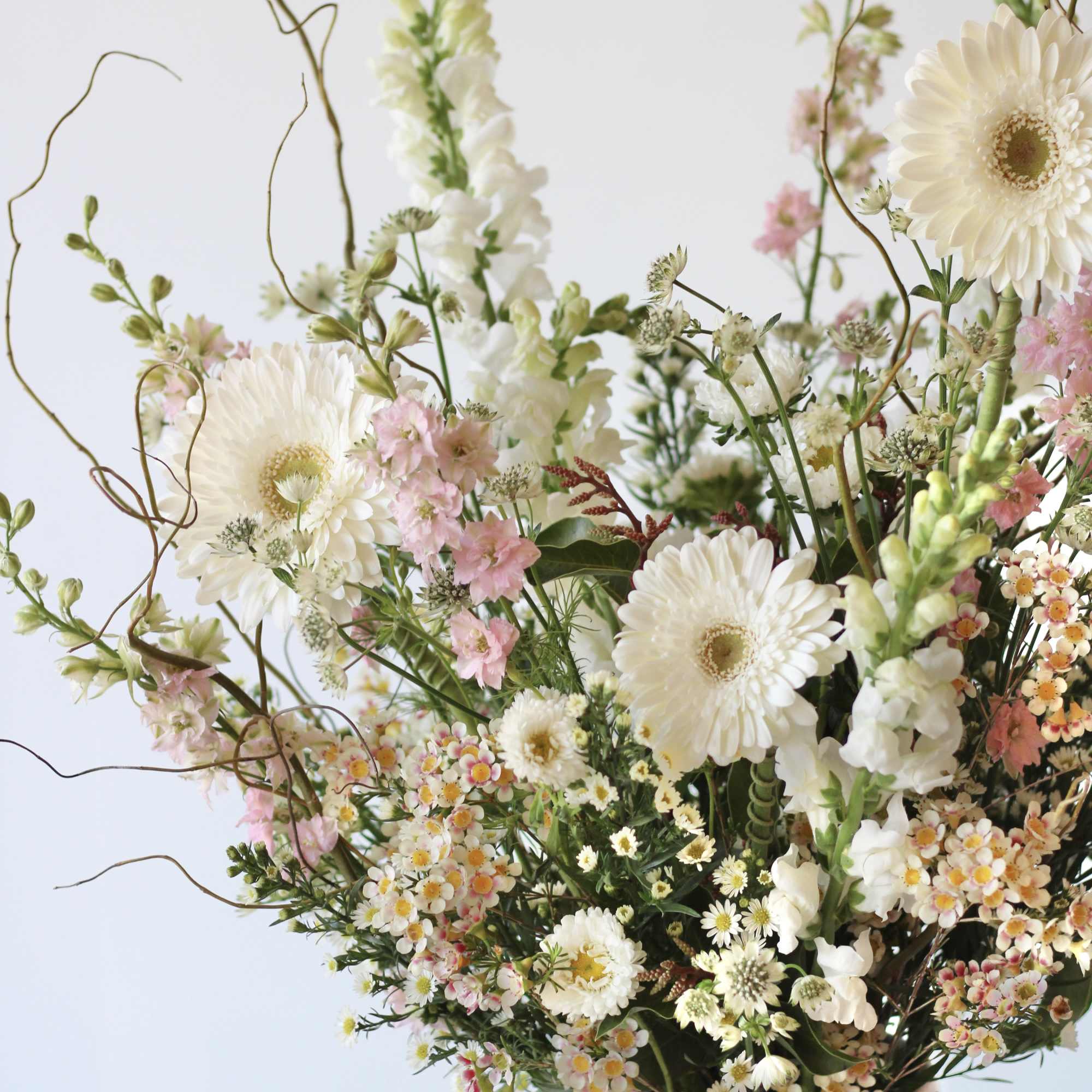 Large pastel floral arrangement in a white pedestal vase