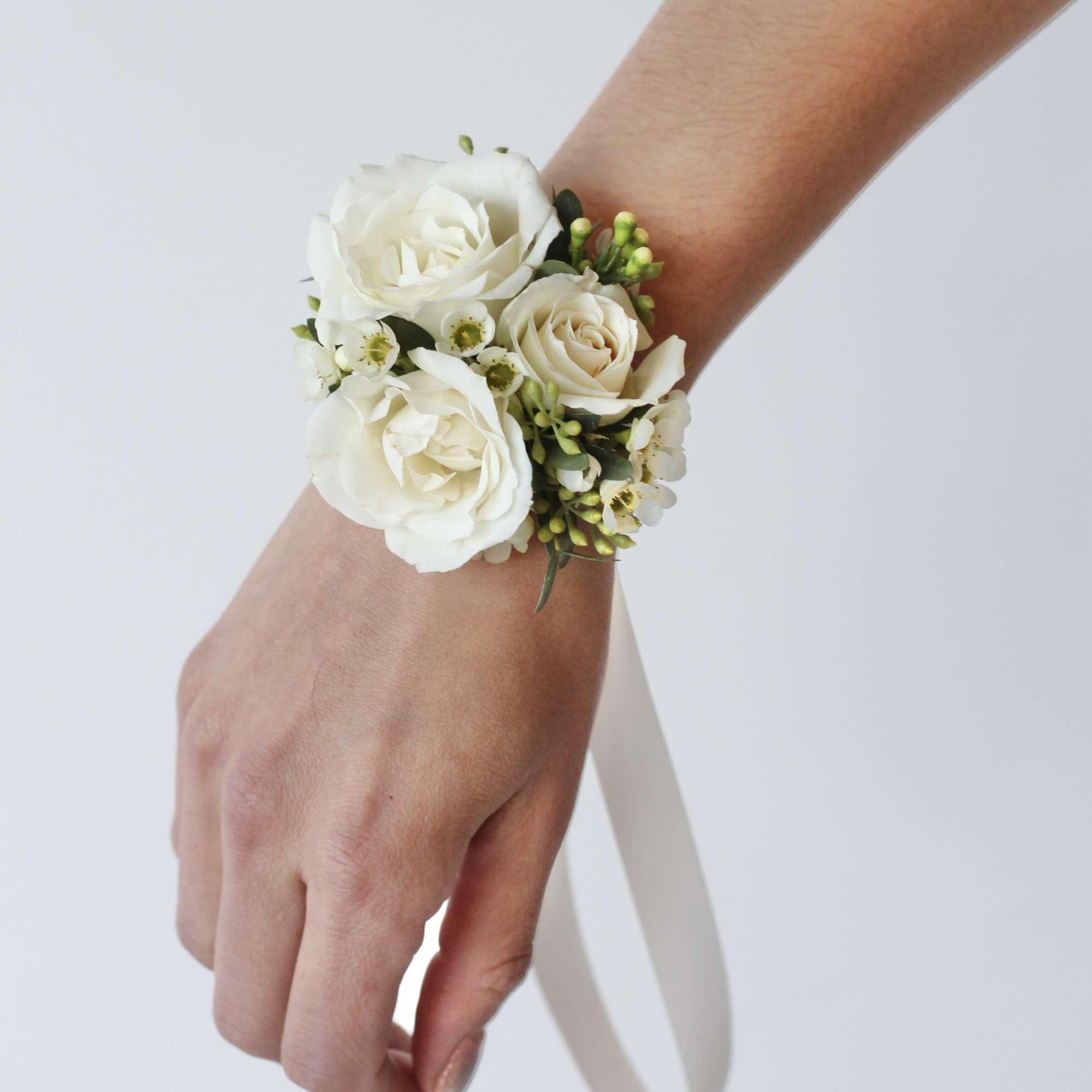 White rose wrist corsage with small white blossoms and ribbon