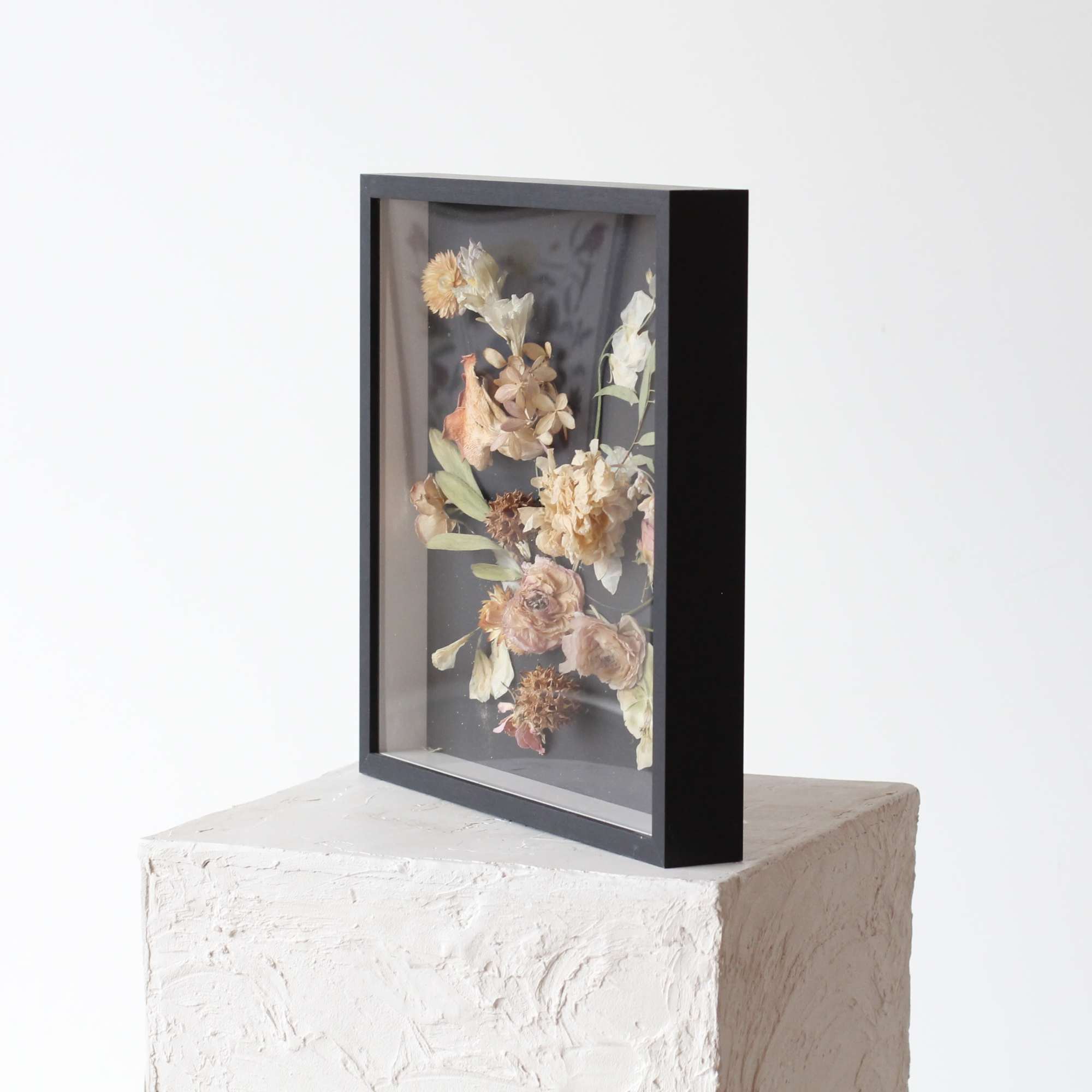 Framed dried flower arrangement in a black shadow box