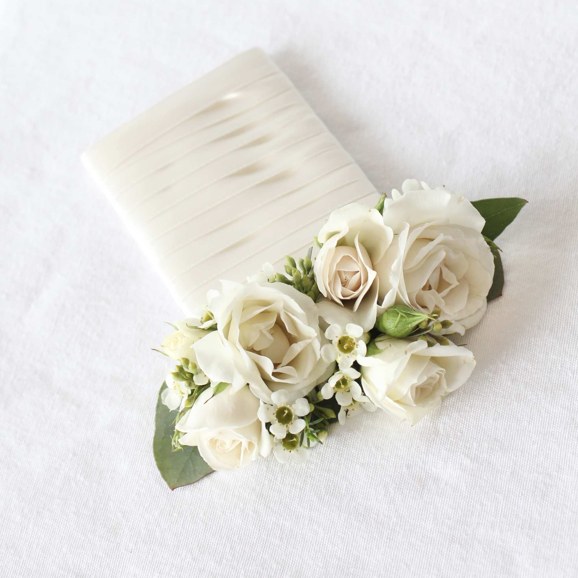 White rose corsage with small white flowers on a ribbon cuff
