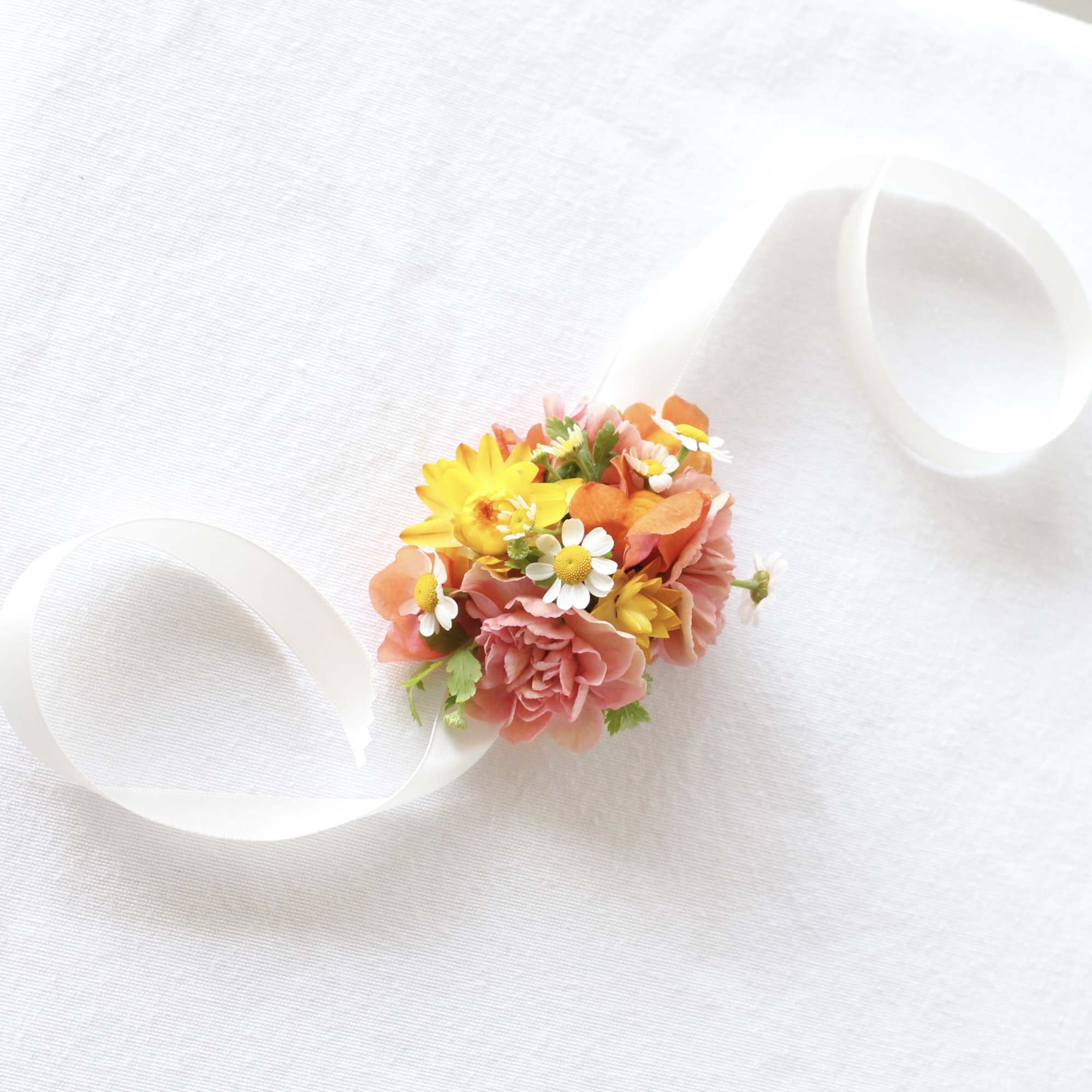 Small bouquet with pink and yellow flowers tied with white ribbon