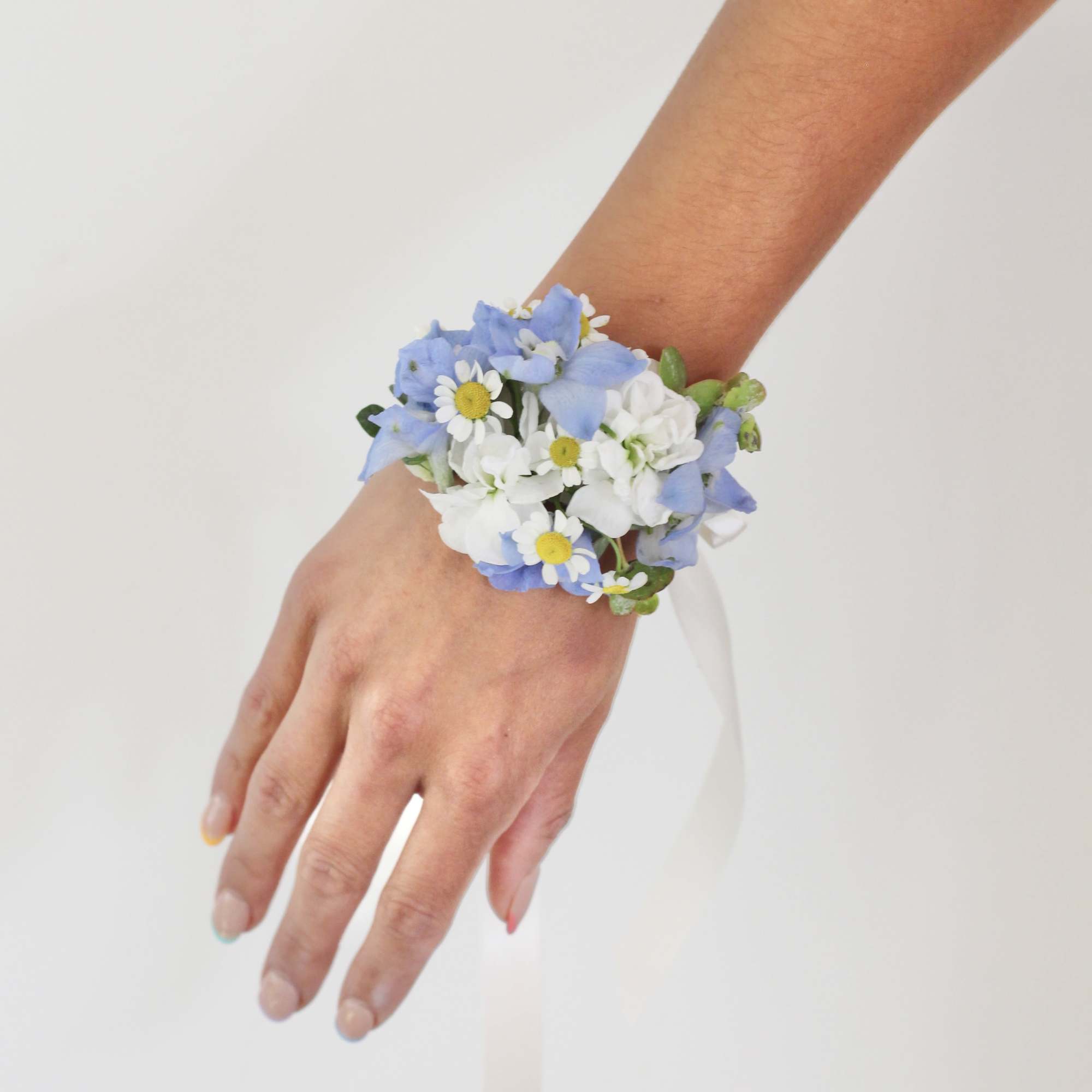 Blue and white floral wrist corsage with a ribbon tie