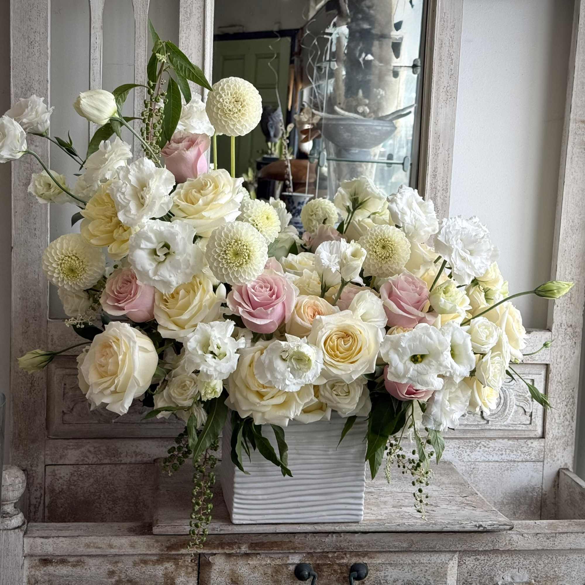 Cream, pink, and white flowers arranged in a white square vase