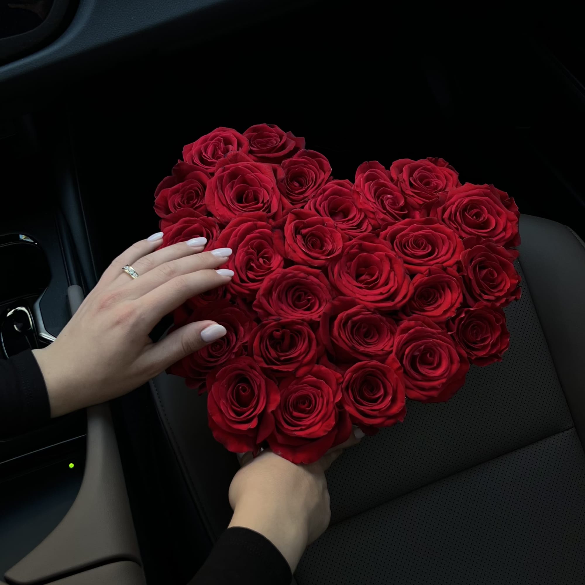 Heart-shaped bouquet of red roses held in a car seat
