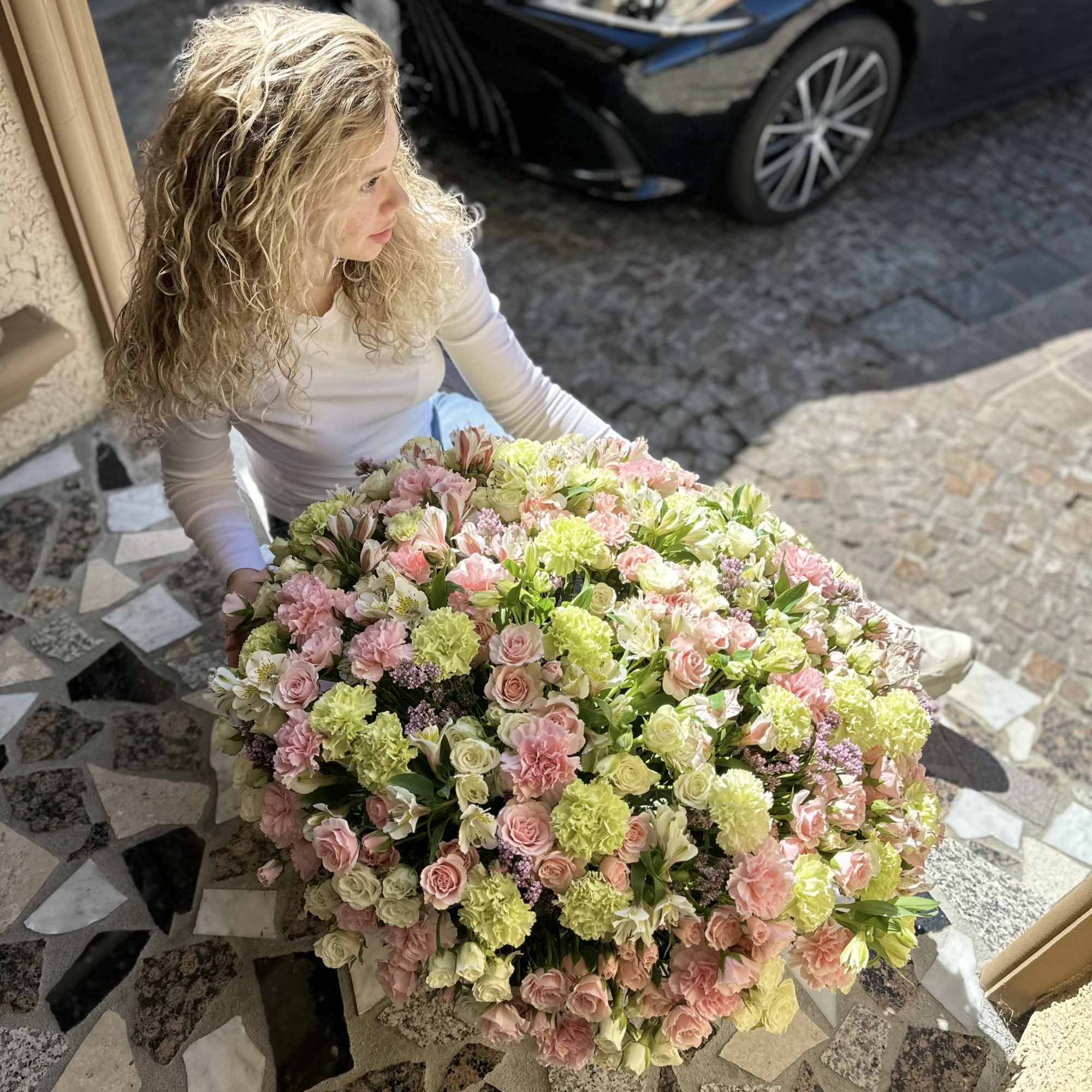 Large bouquet of pink, cream, and green flowers held by a woman
