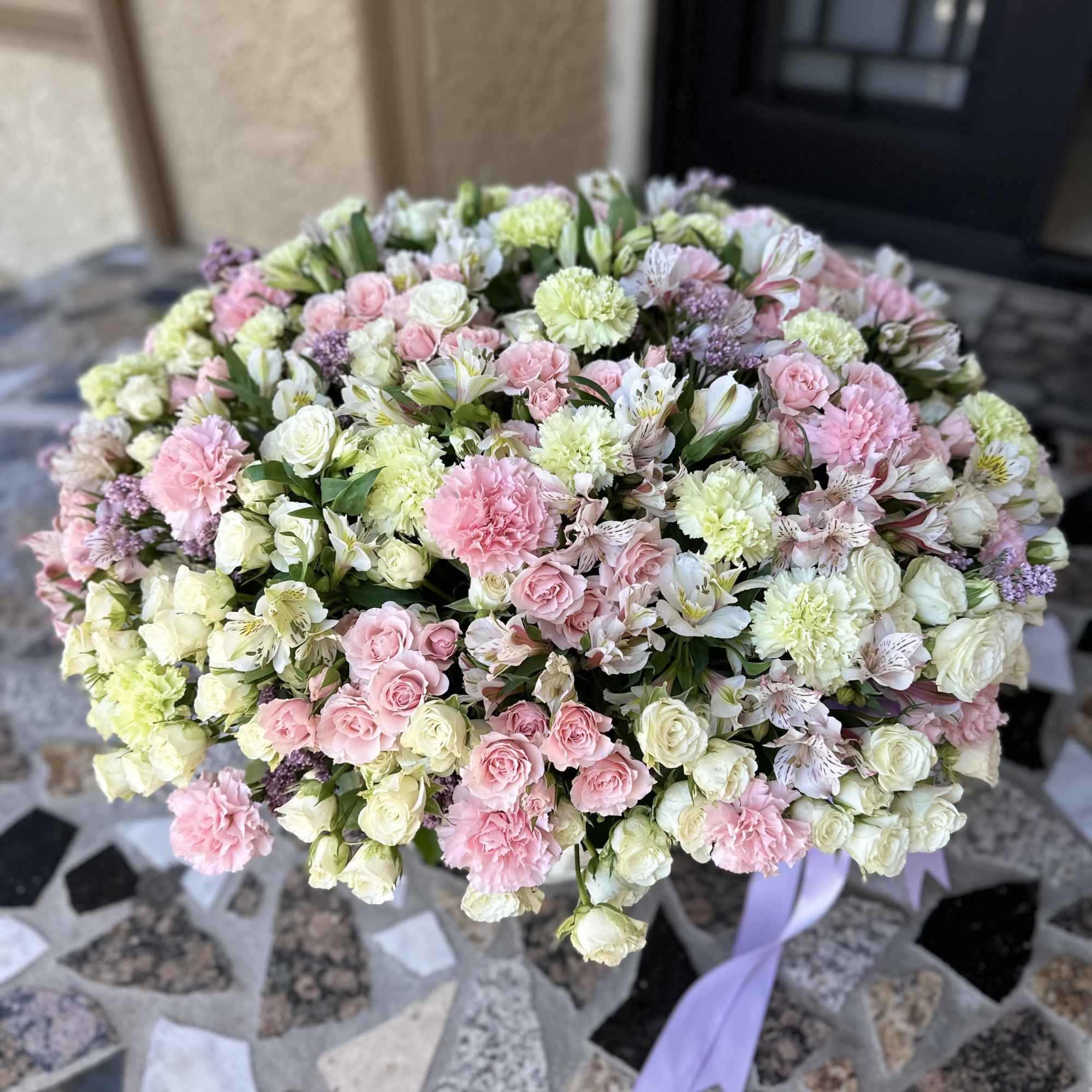 Large pastel bouquet of pink and white flowers with a lavender ribbon