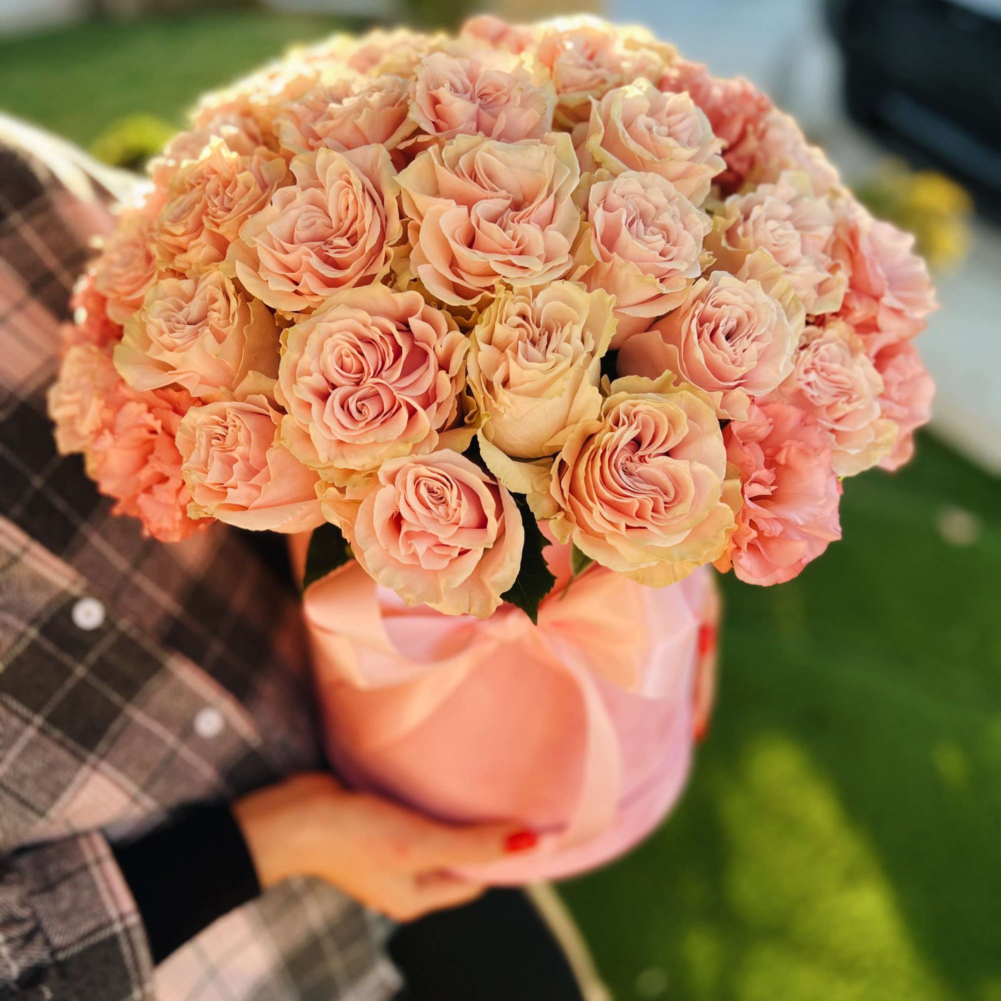 Bouquet of peach and blush roses wrapped in pink paper