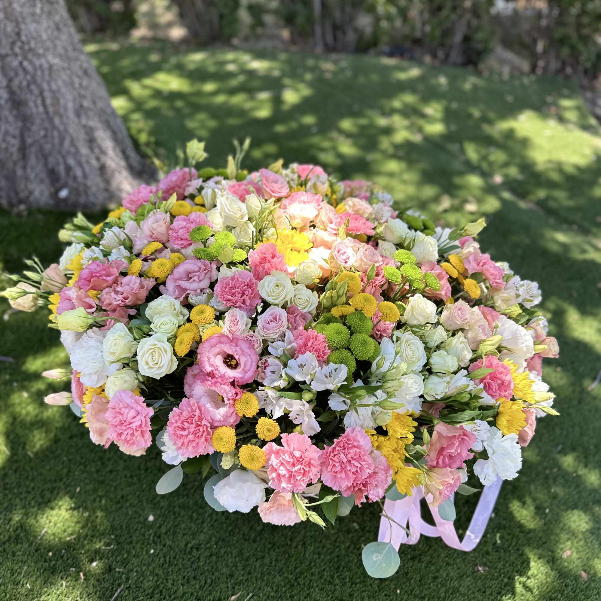 Large pastel bouquet of pink, white, and yellow flowers with ribbon tails