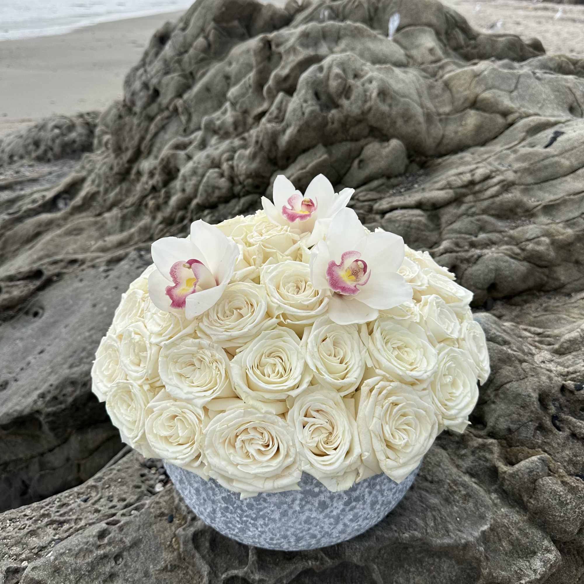 White rose bouquet with white orchids in a round vase