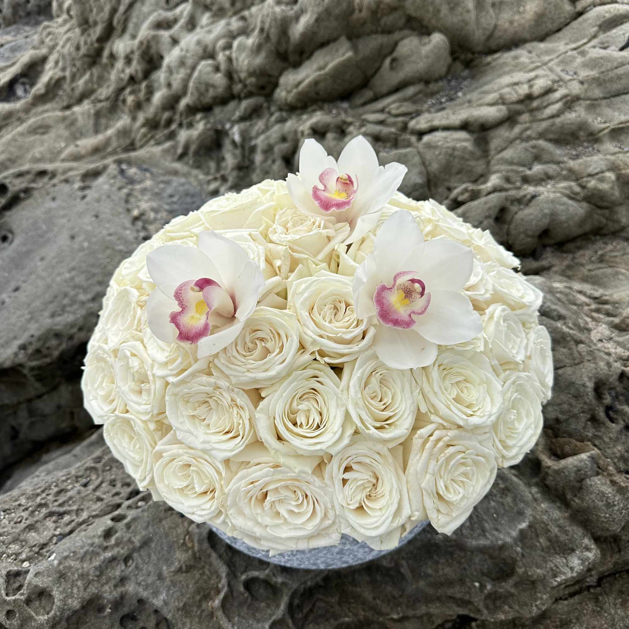White rose bouquet with three white orchids and pink centers