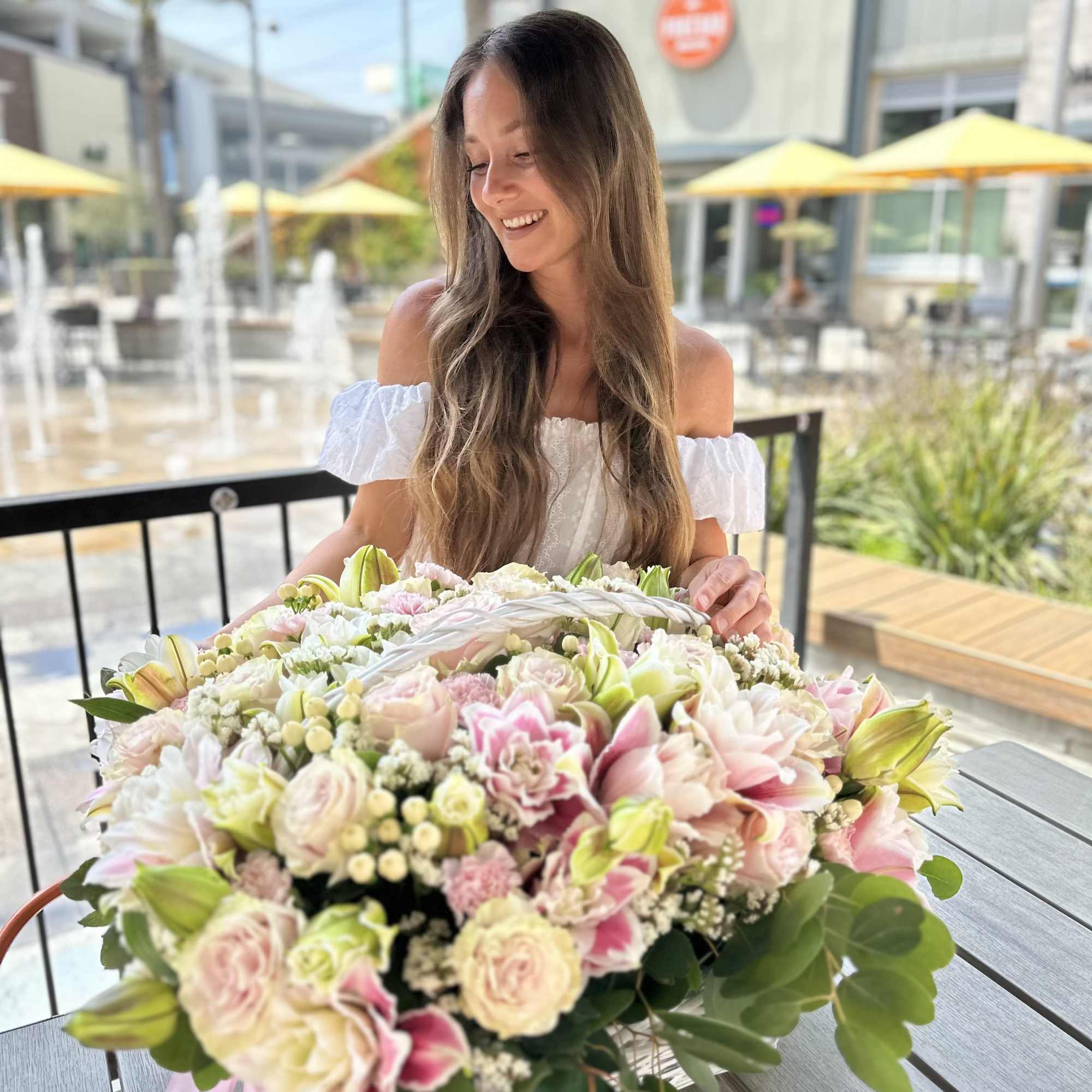 Large pastel bouquet of roses and lilies held by a smiling woman