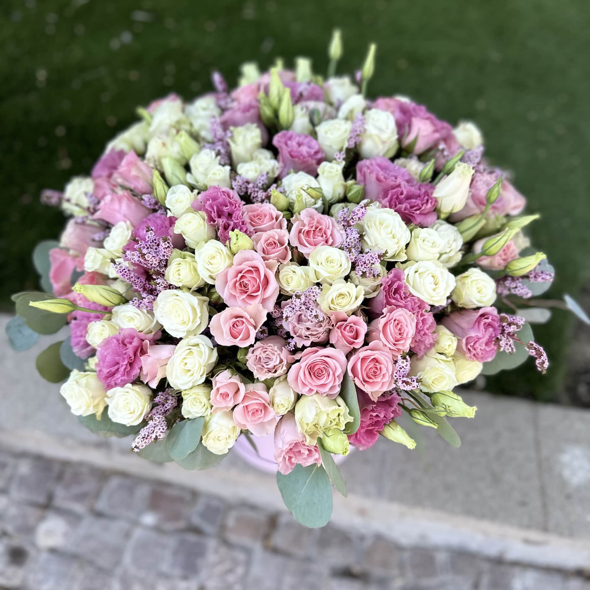 Round bouquet of pink and white roses with small purple filler flowers