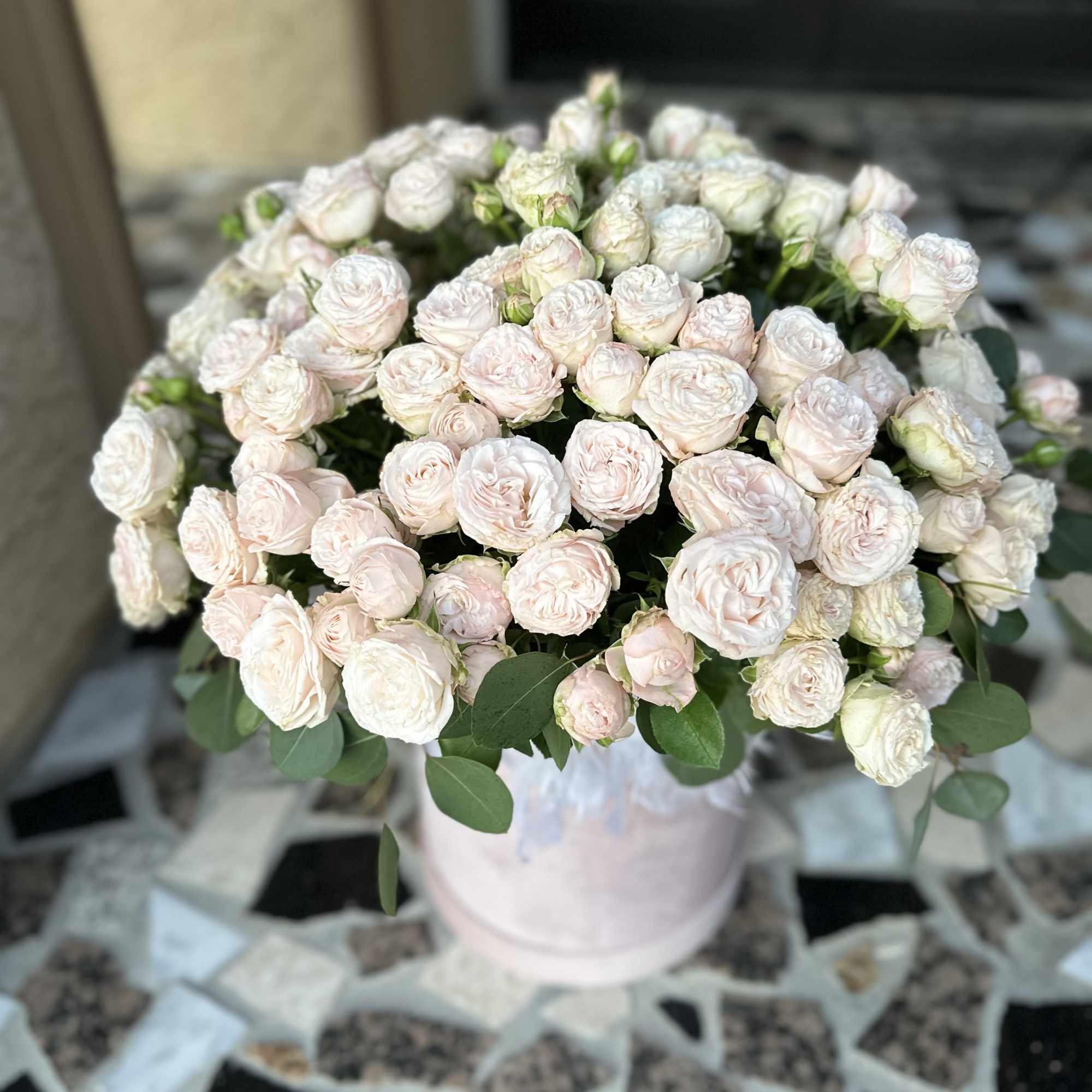 Bouquet of pale pink spray roses in a light pink vase