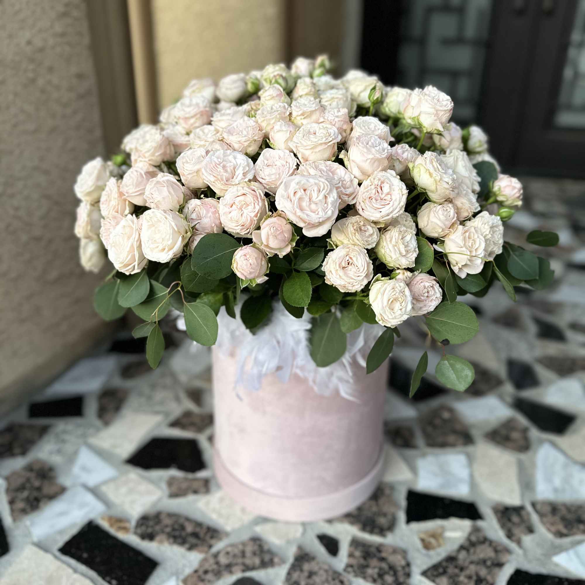 Pale pink roses arranged in a pink hatbox