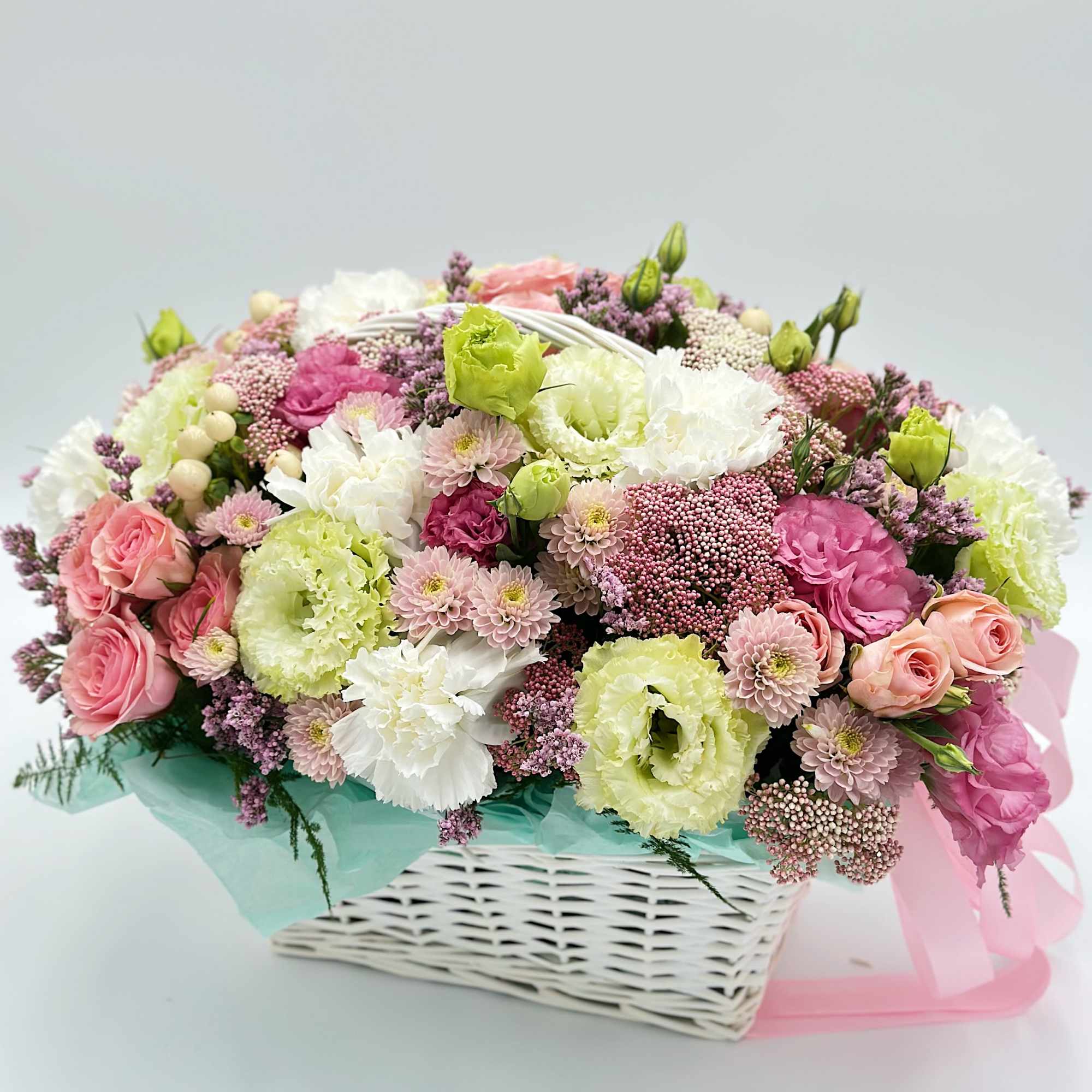 Pink and white mixed flower arrangement in a white basket