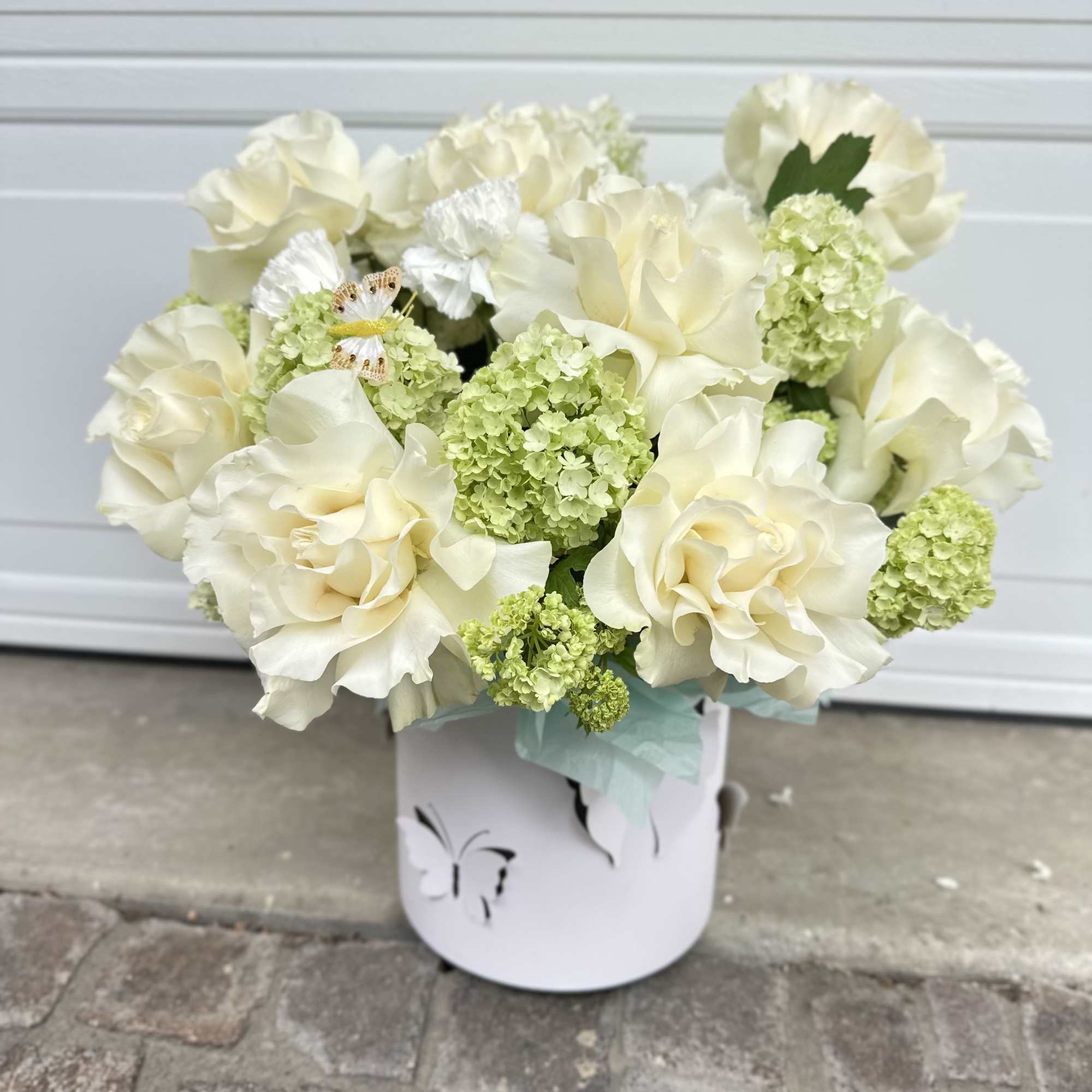 Cream roses and green hydrangeas in a white container