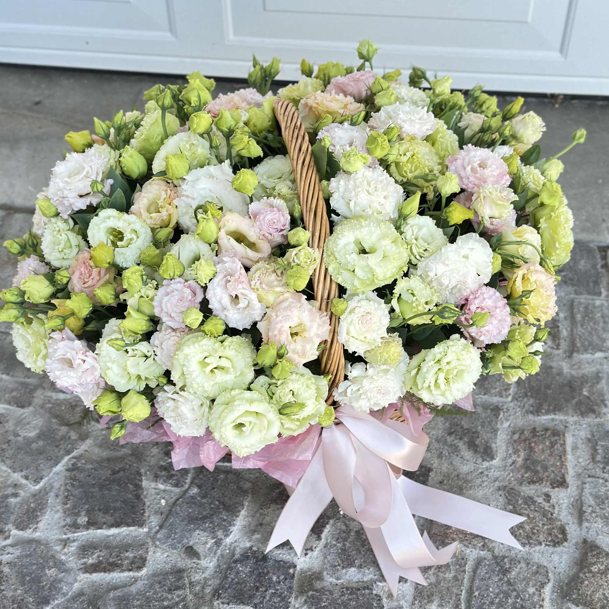 Basket of pastel lisianthus flowers with a pink ribbon